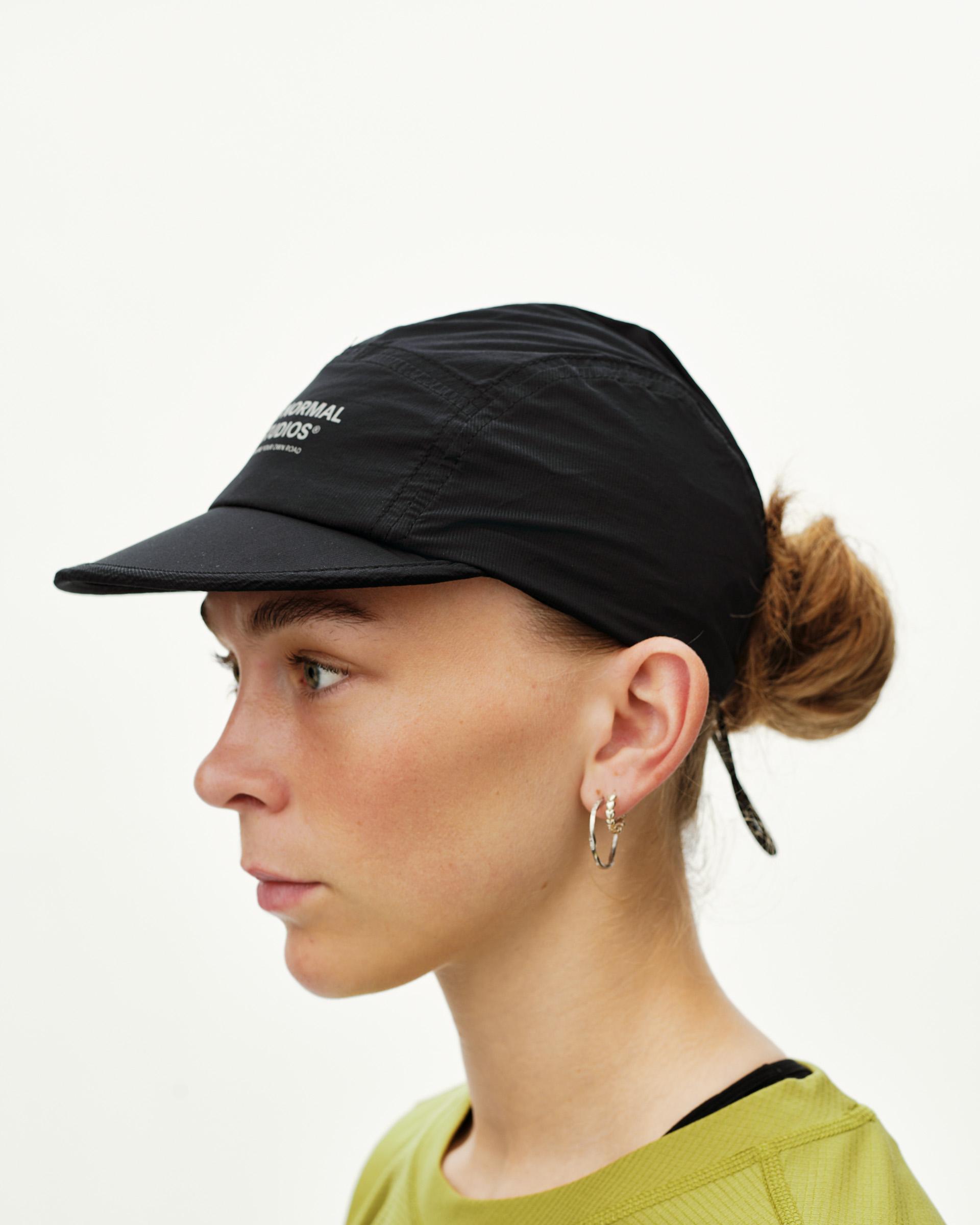 Black Balance Cap on model, side view with open-back design and logo print on brim