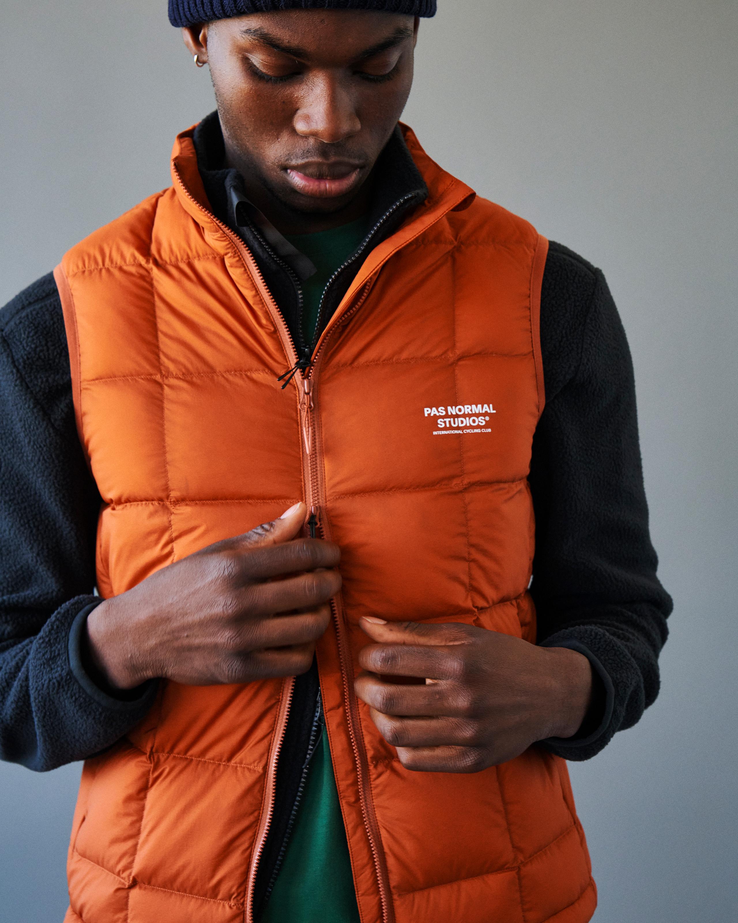 Orange Off-Race Down vest on model with quilted panels and white chest logo