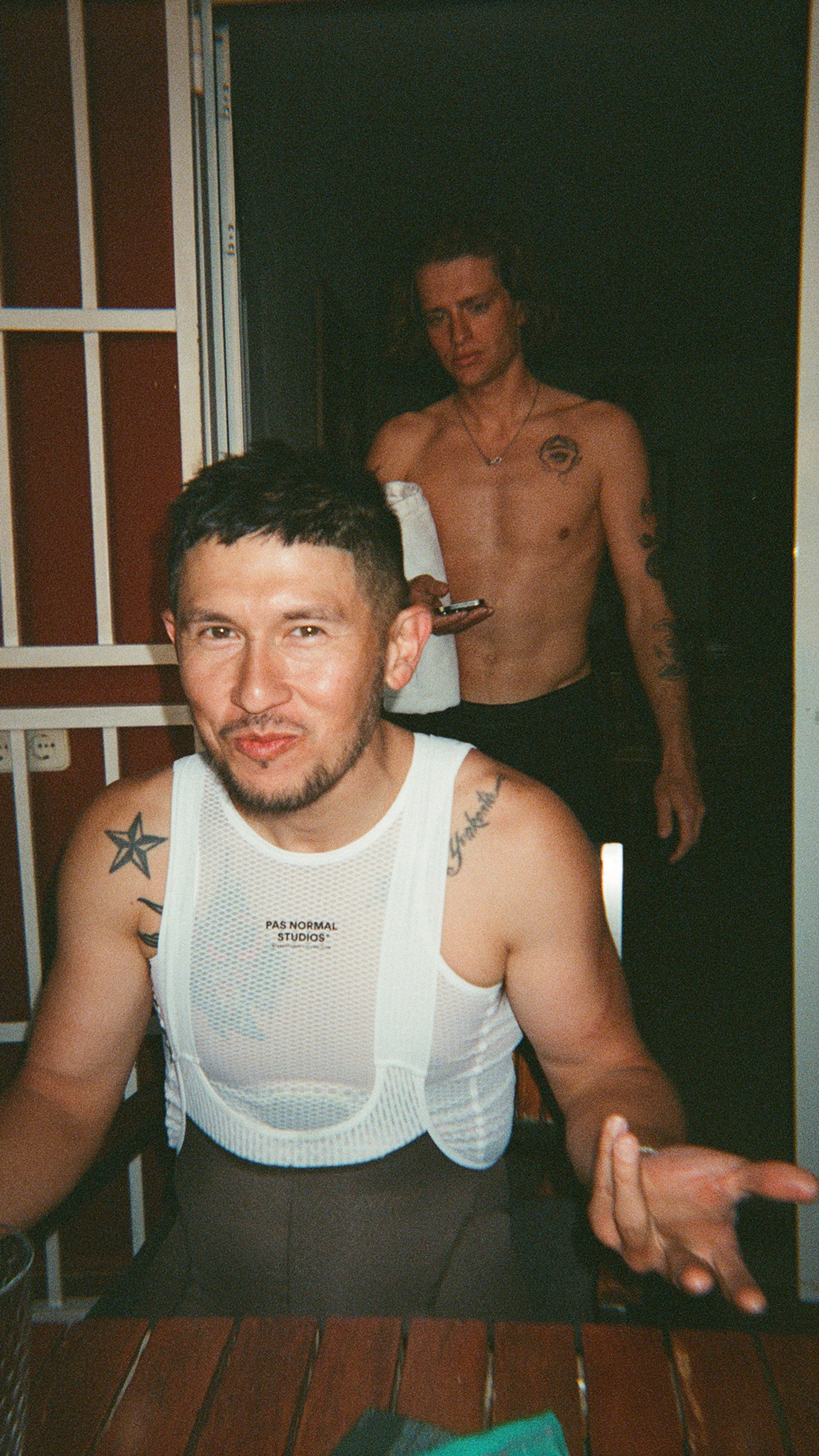 Model wearing white mesh base layer with chest branding in indoor setting