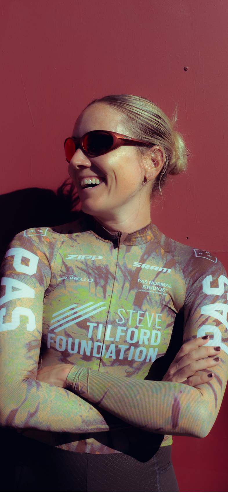 Model wearing Steve Tilford Foundation racing jersey with multicolored pattern and sponsor logos