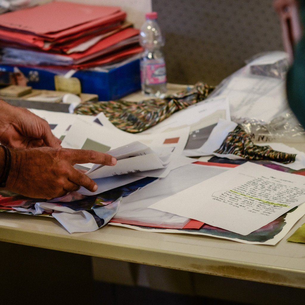Designer hands sorting through fabric swatches and color samples on workspace table