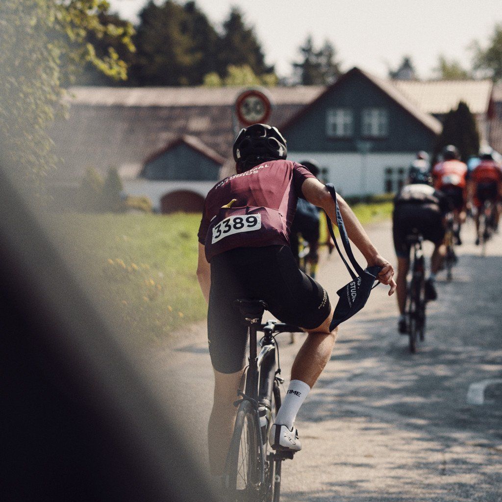 Cyclist in burgundy jersey competing in time trial with race number 3389