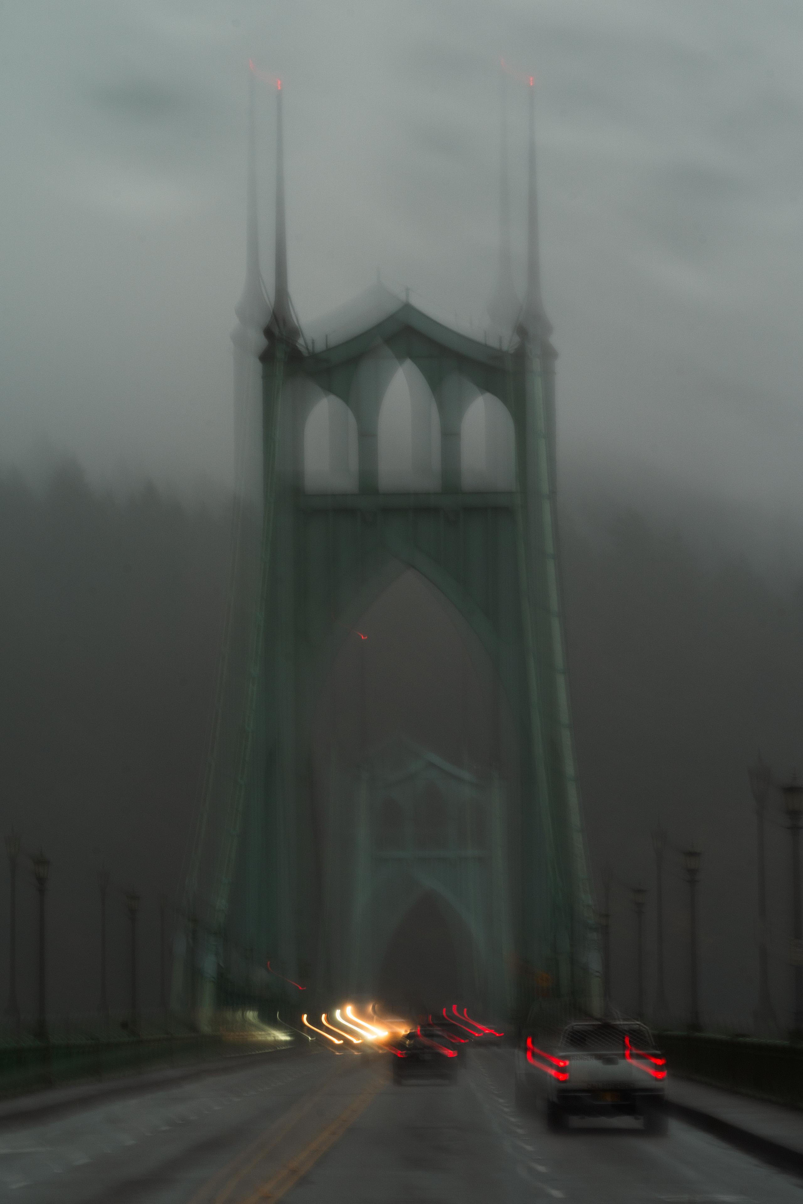 Gothic bridge in fog with car headlights and taillights streaking below