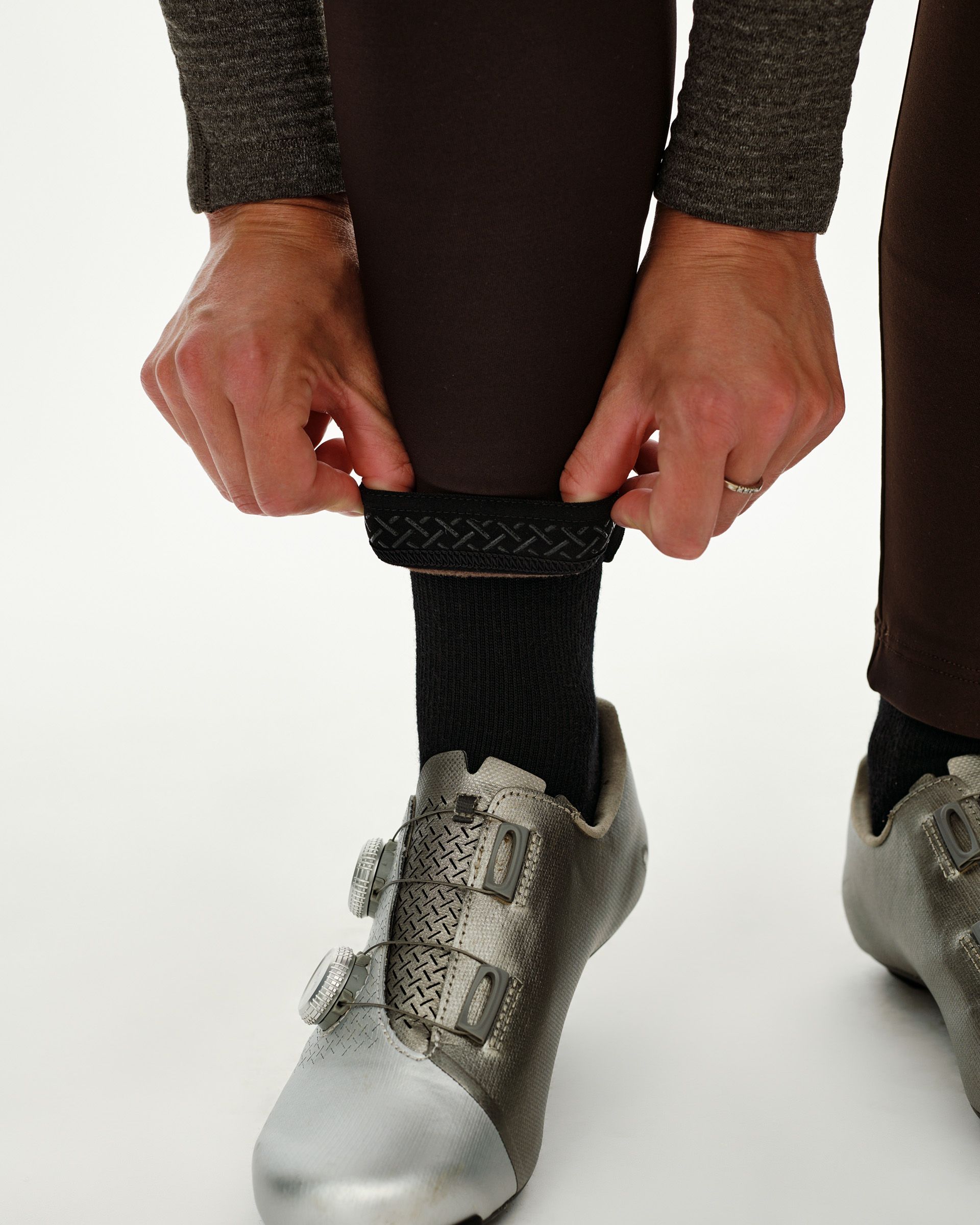 Dark Coffee brown Mechanism Thermal Long cycling bibs, detail on model showing leg gripper band adjusted over cycling sock