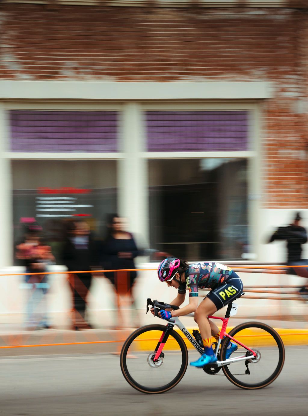 Cyclist in colorful jersey and dark shorts racing on time trial bike through urban street