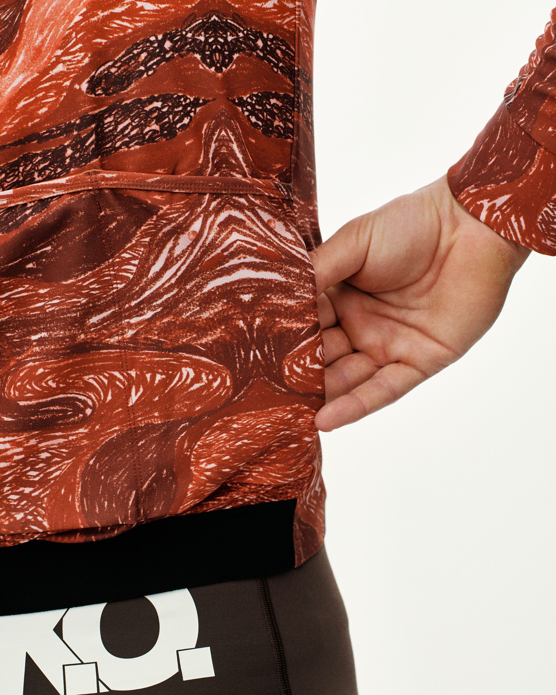 Red T.K.O. Woven long sleeve cycling jersey, side detail on model showing rear pocket opening with all-over print
