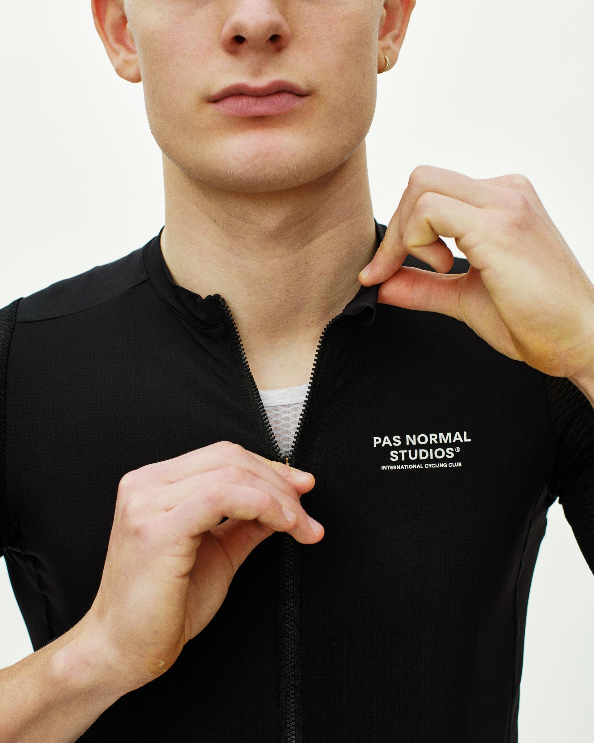 Black Essential Light cycling jersey on model with quarter zip and white chest logo