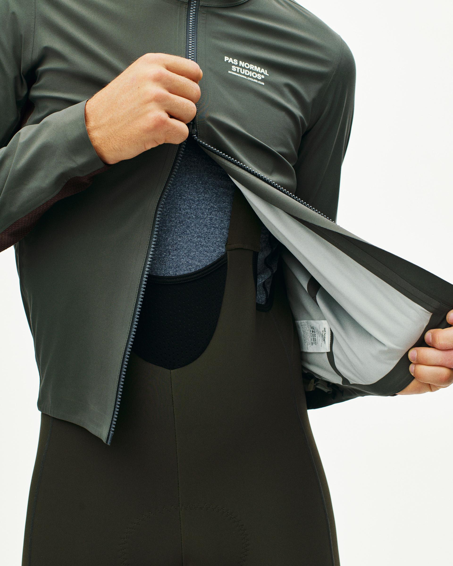 Dark Grey Mechanism Shell cycling jacket on model, detail view with zip open showing grey inner lining