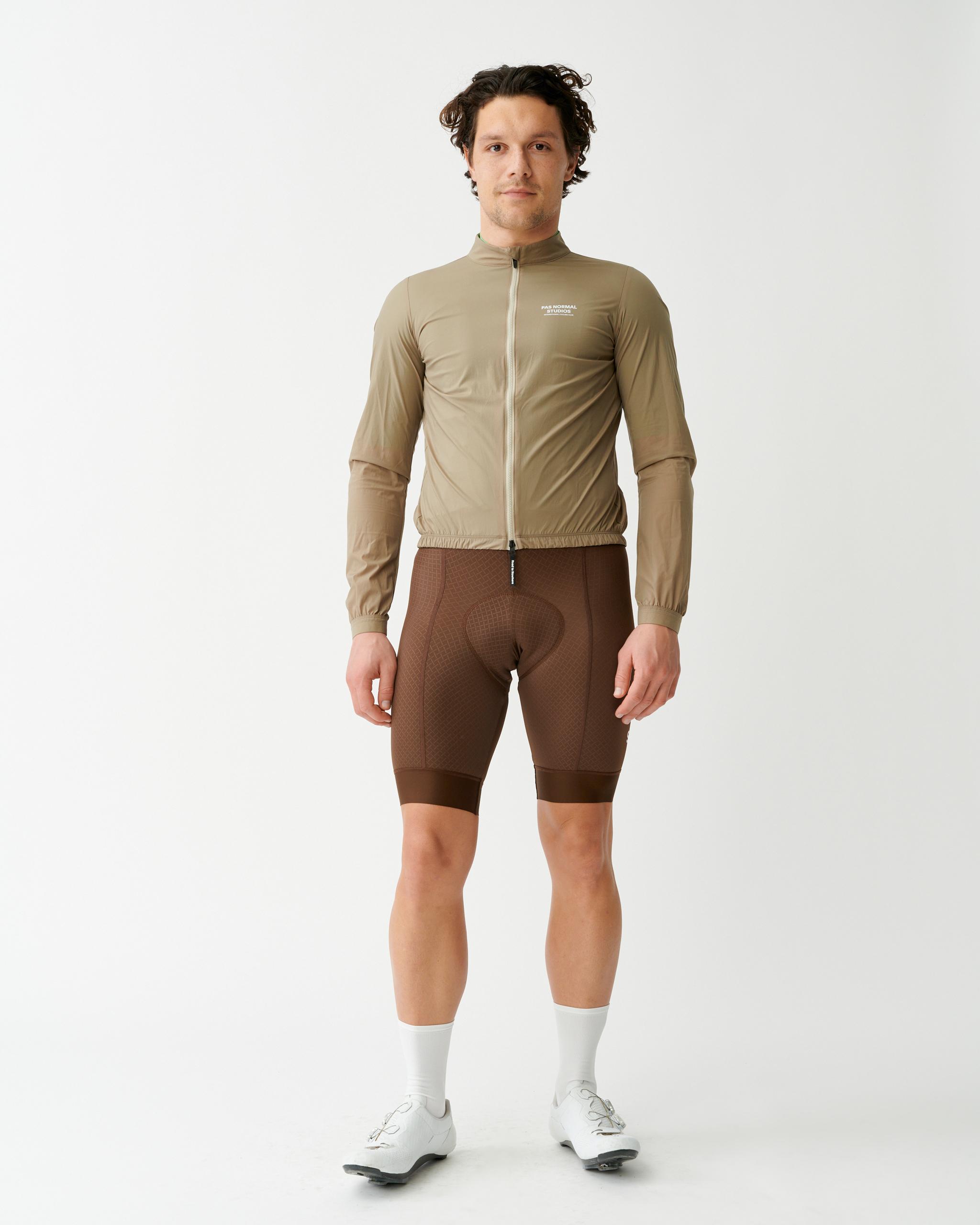 Beige Mechanism Stow Away cycling jacket on model with full zip and elastic hem