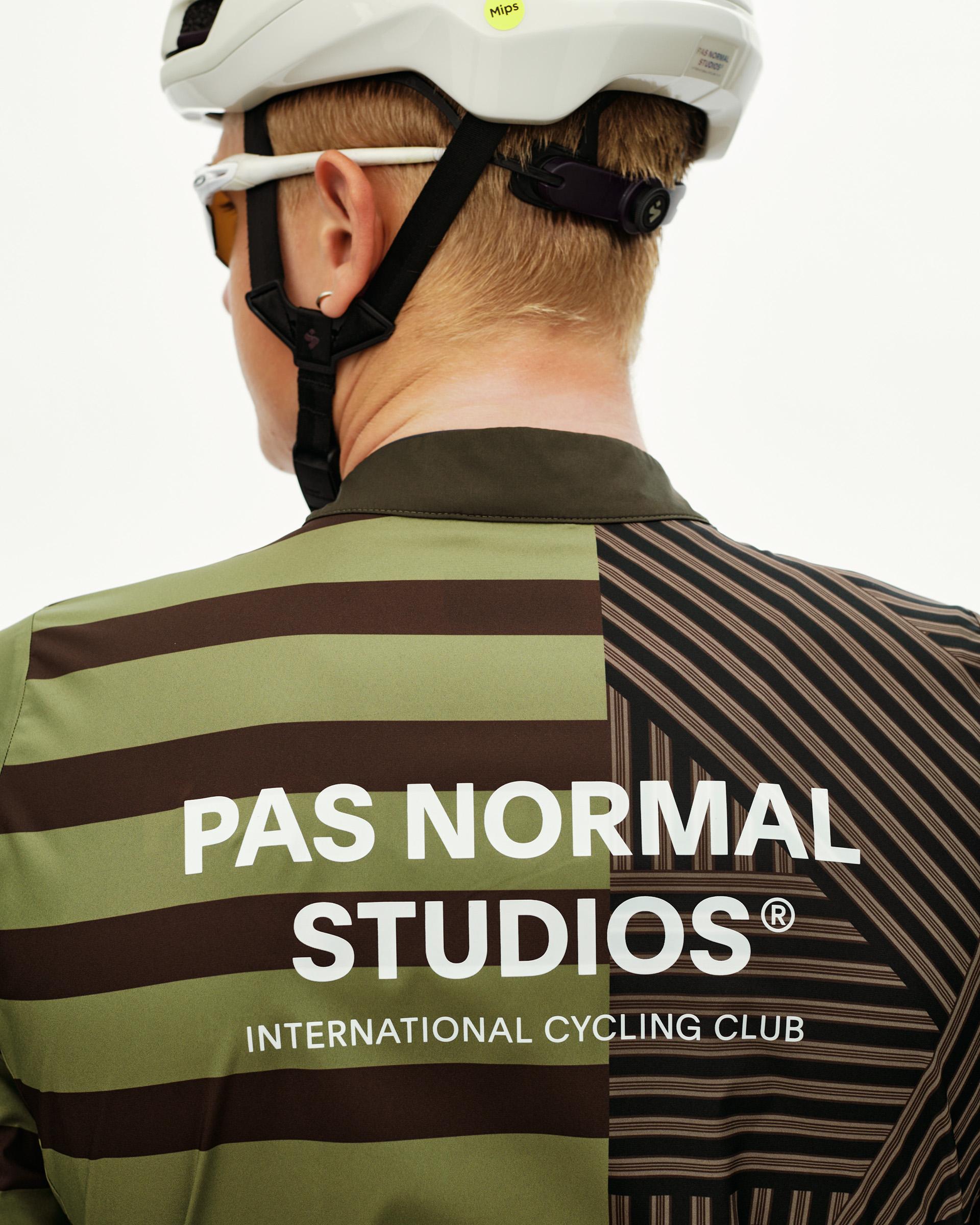 International Green Mechanism Stow Away cycling jacket on model, rear view with mixed stripe print and white back logo