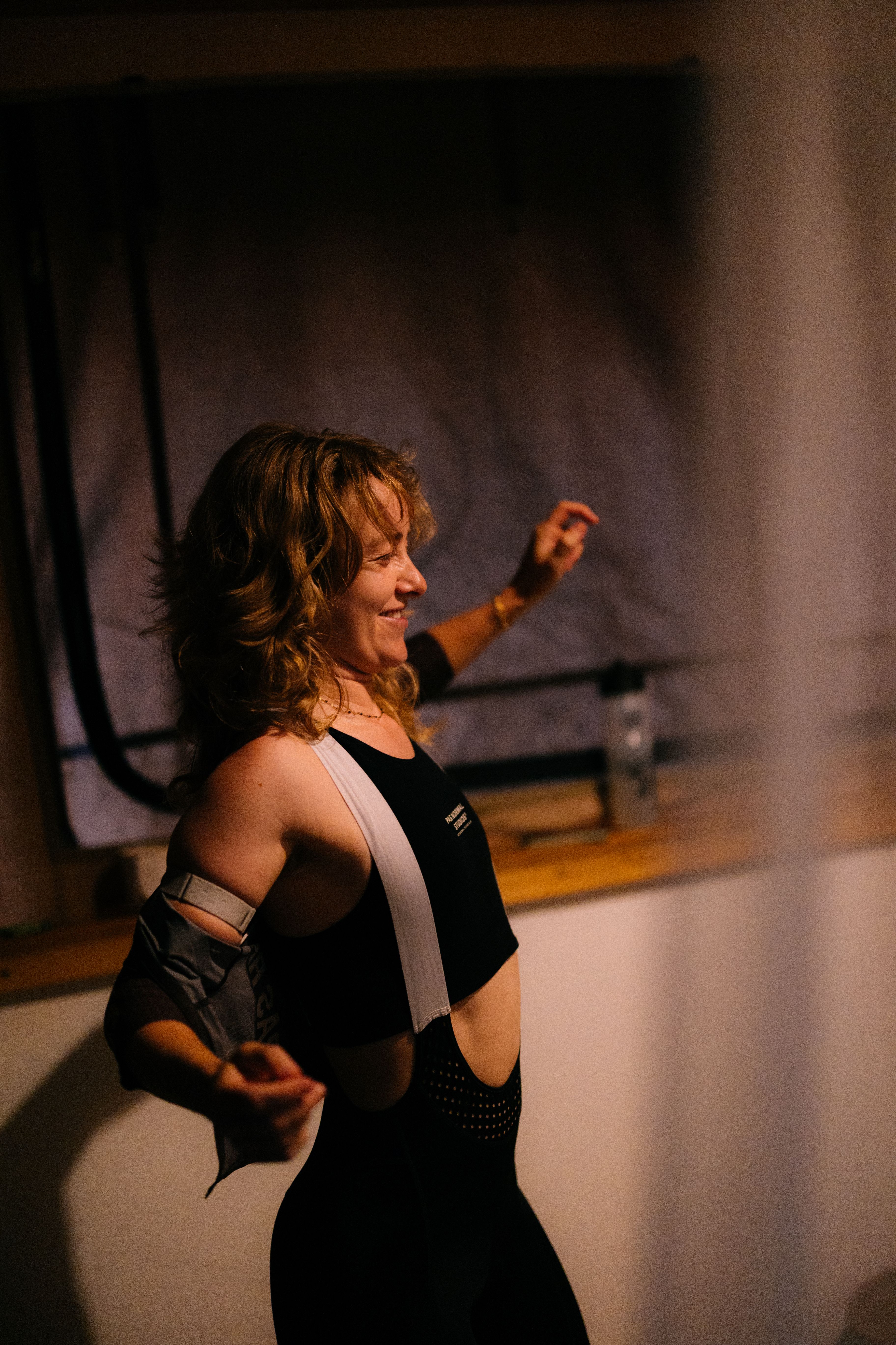 Model wearing black cycling sportswear with white shoulder strap detail indoors