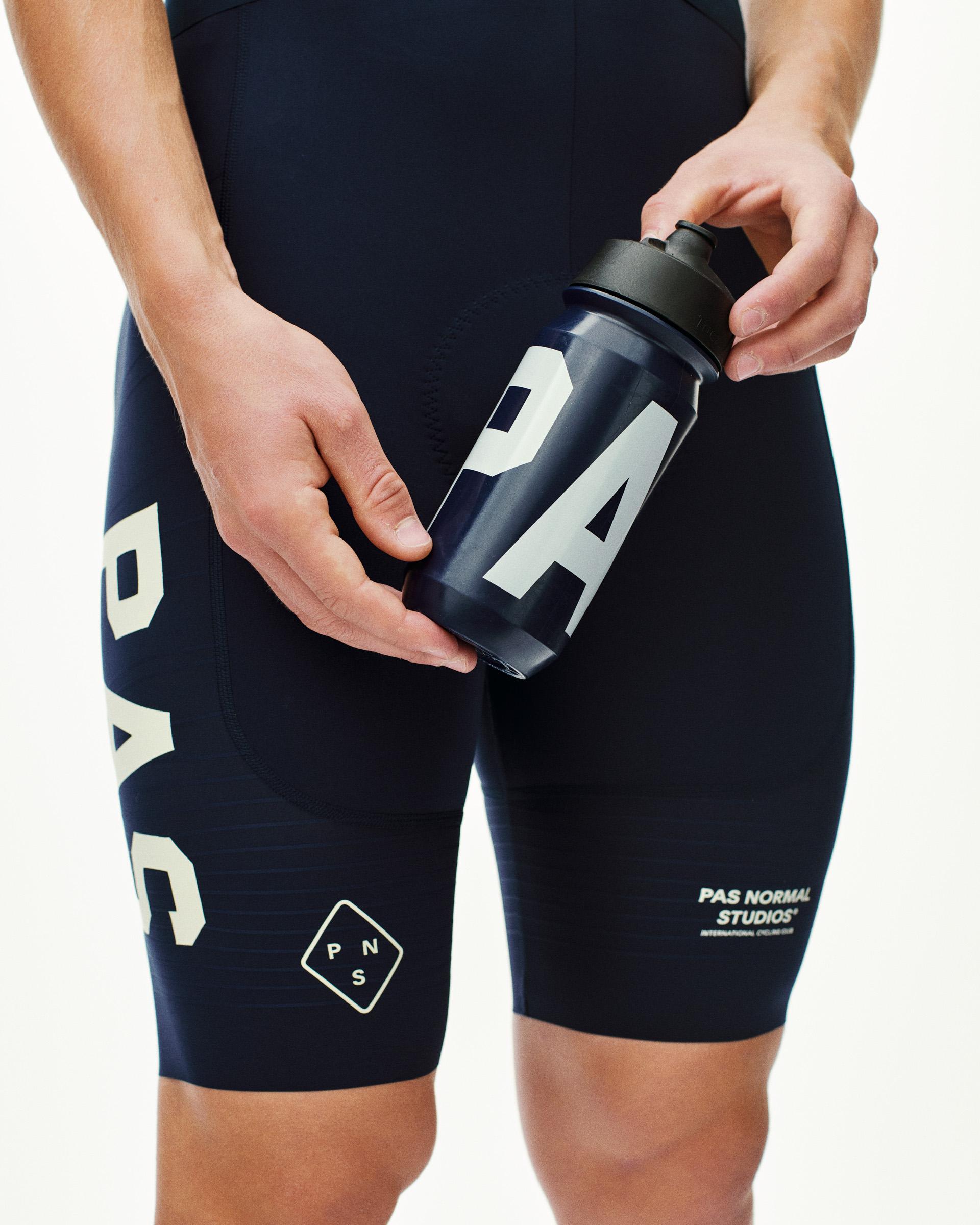 Navy PAS water bottle held by model with white logo graphics