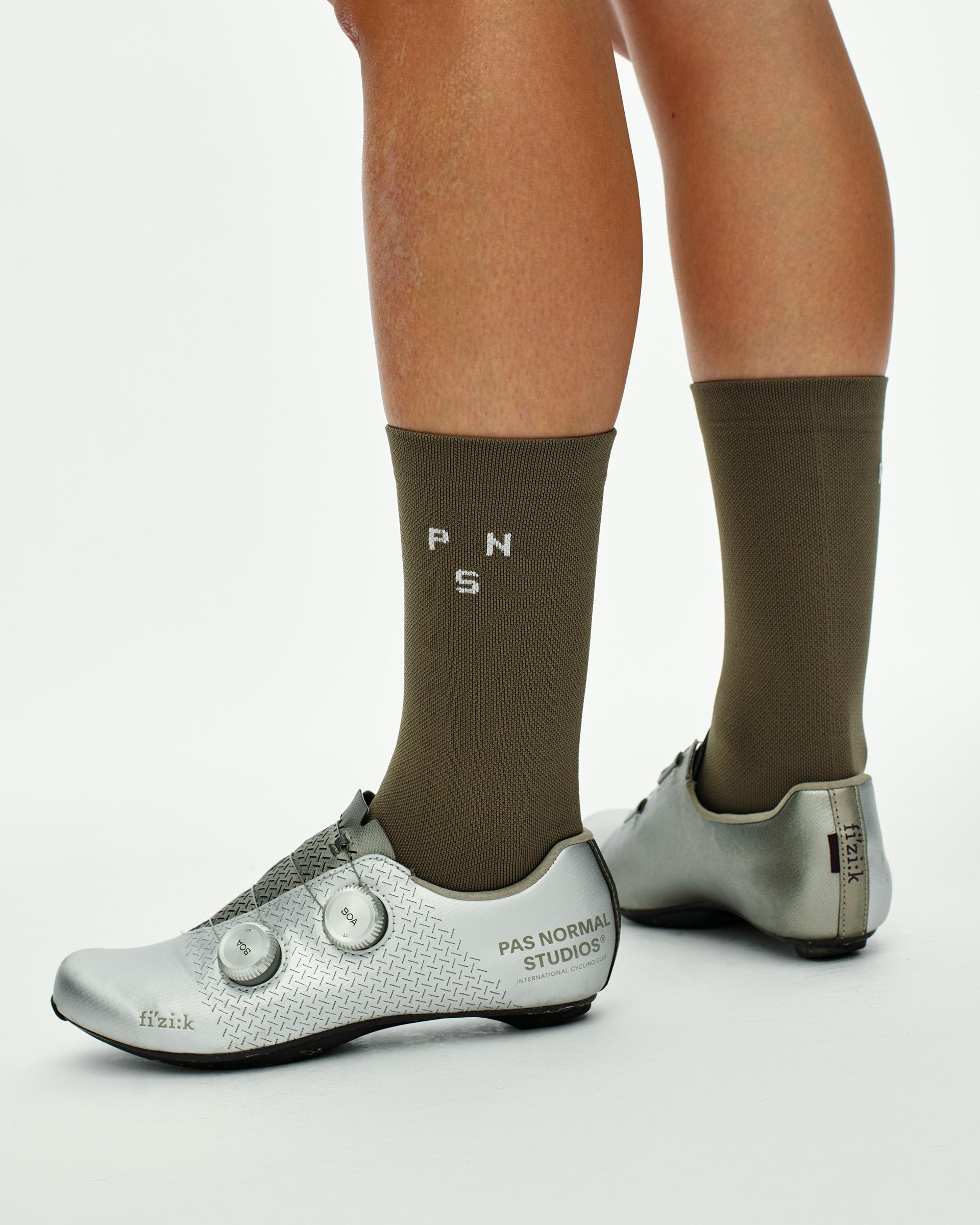 Earth khaki Essential cycling socks on model, three-quarter view with silver Fizik road shoes