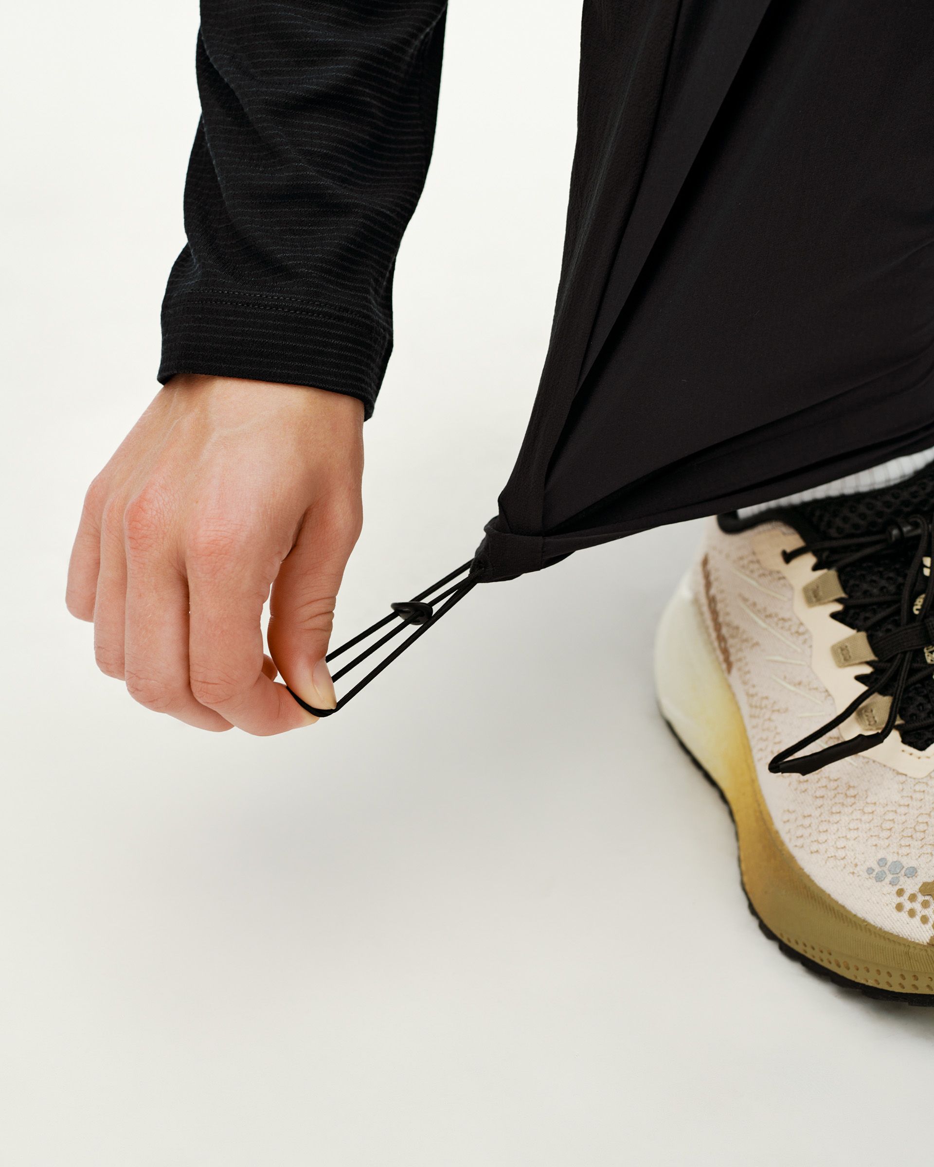 Black Balance Performance pants, detail view of drawcord hem adjustment on model