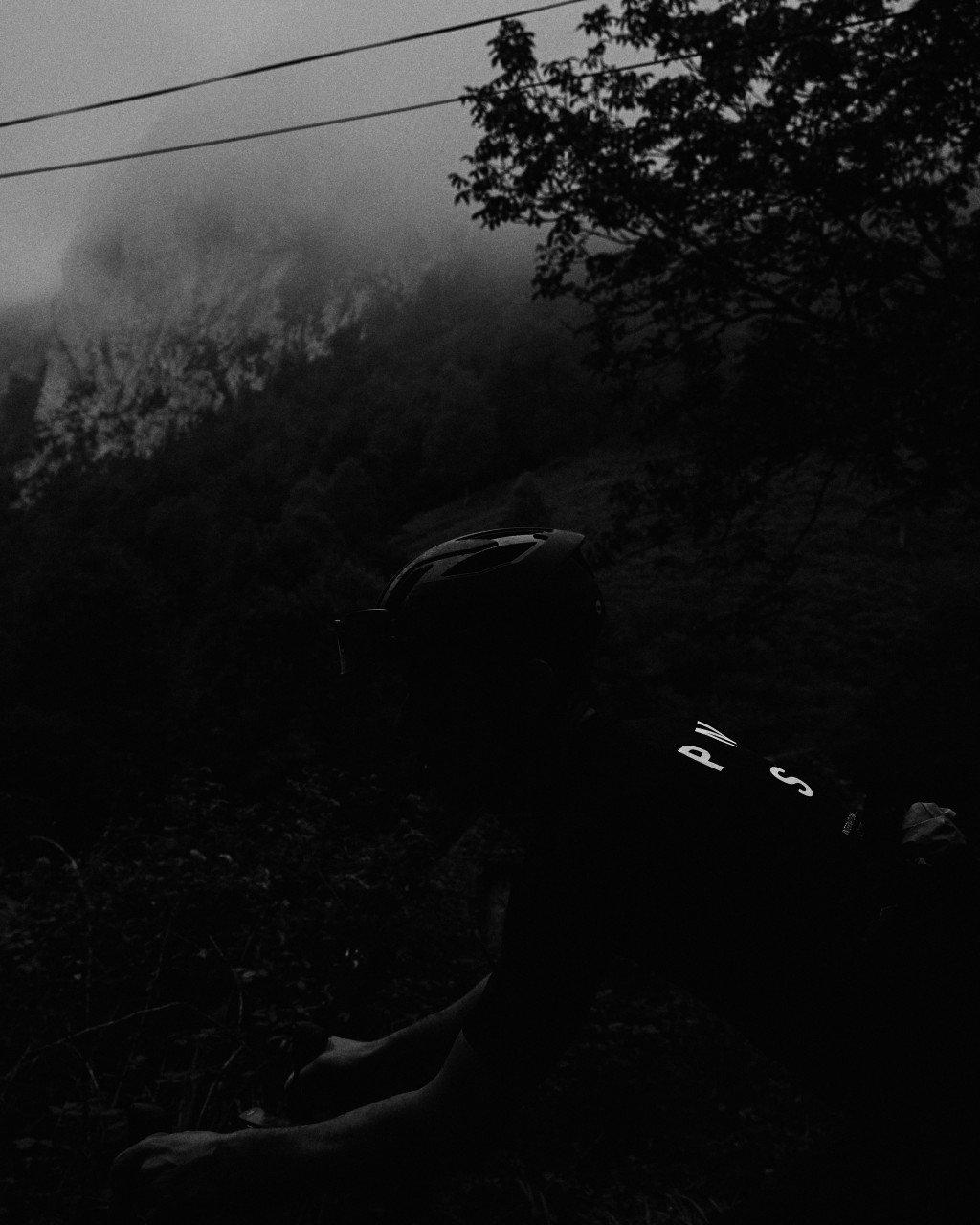Cyclist resting on roadside in misty landscape with bicycle and helmet