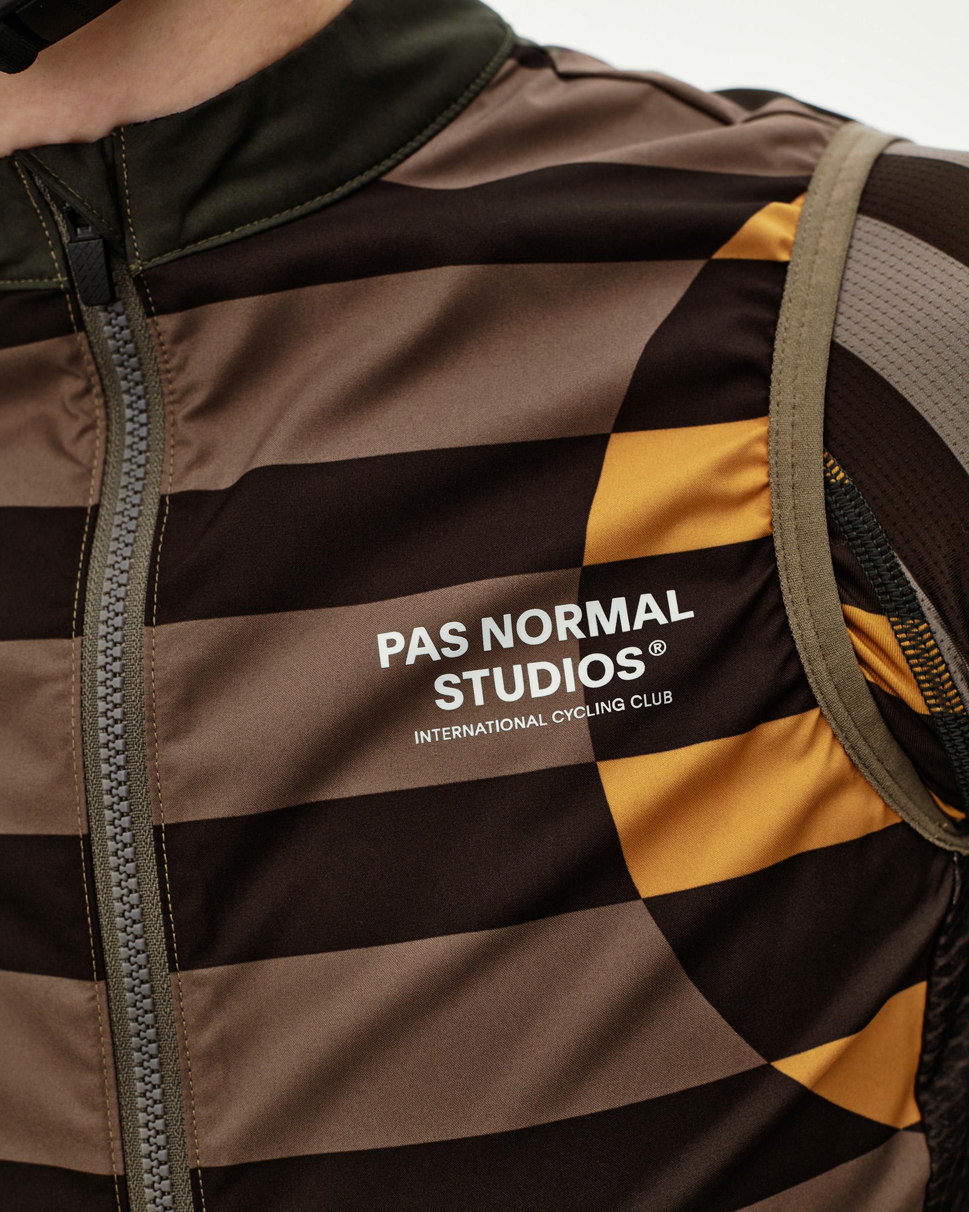 International Earth brown Mechanism Stow Away cycling gilet, front detail on model with stripe print and chest logo