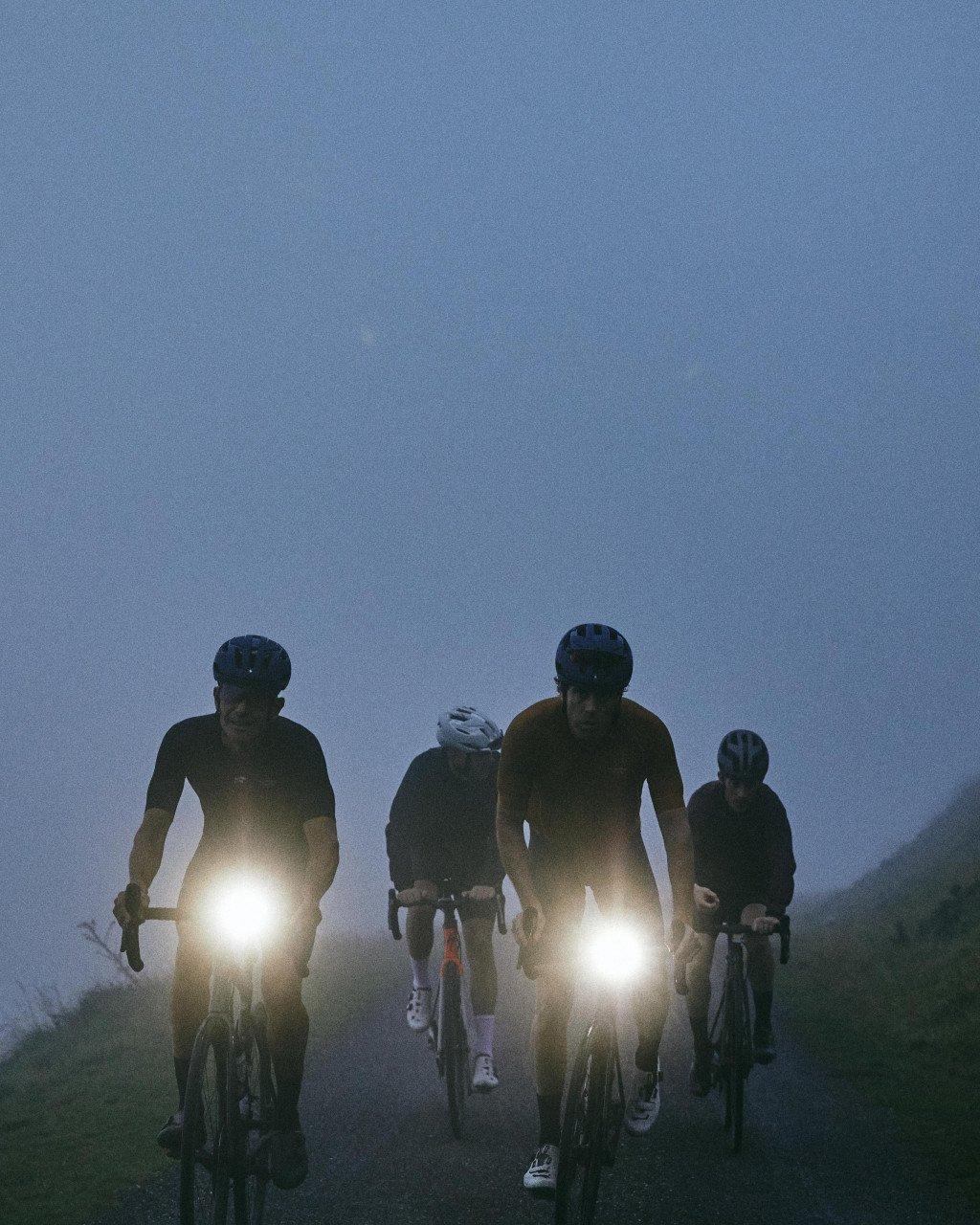 Cyclists riding with bike lights during dusk in mountainous terrain
