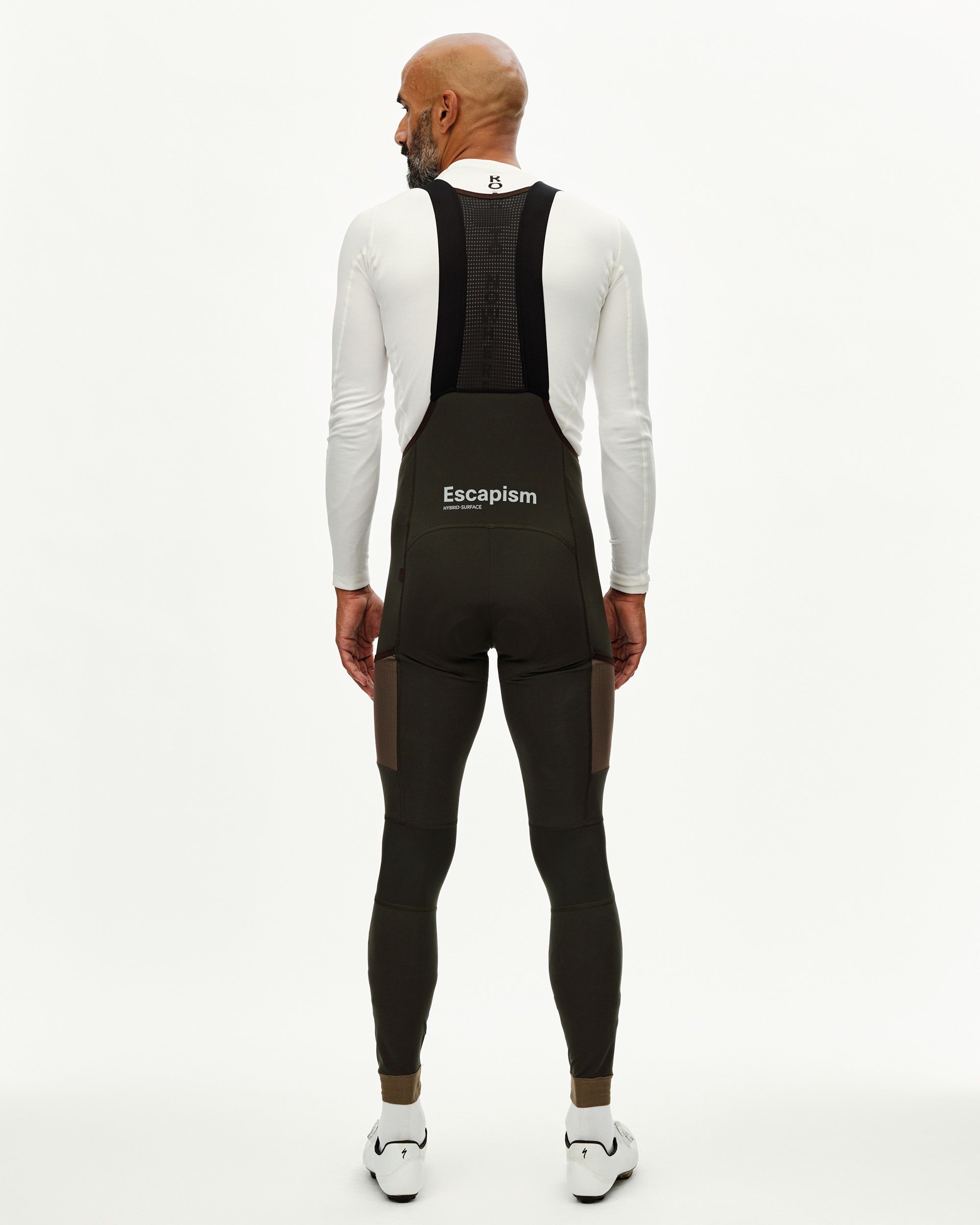 Dark Olive Escapism Long Cargo cycling bibs on model, rear view with contrast panels and white chest logo