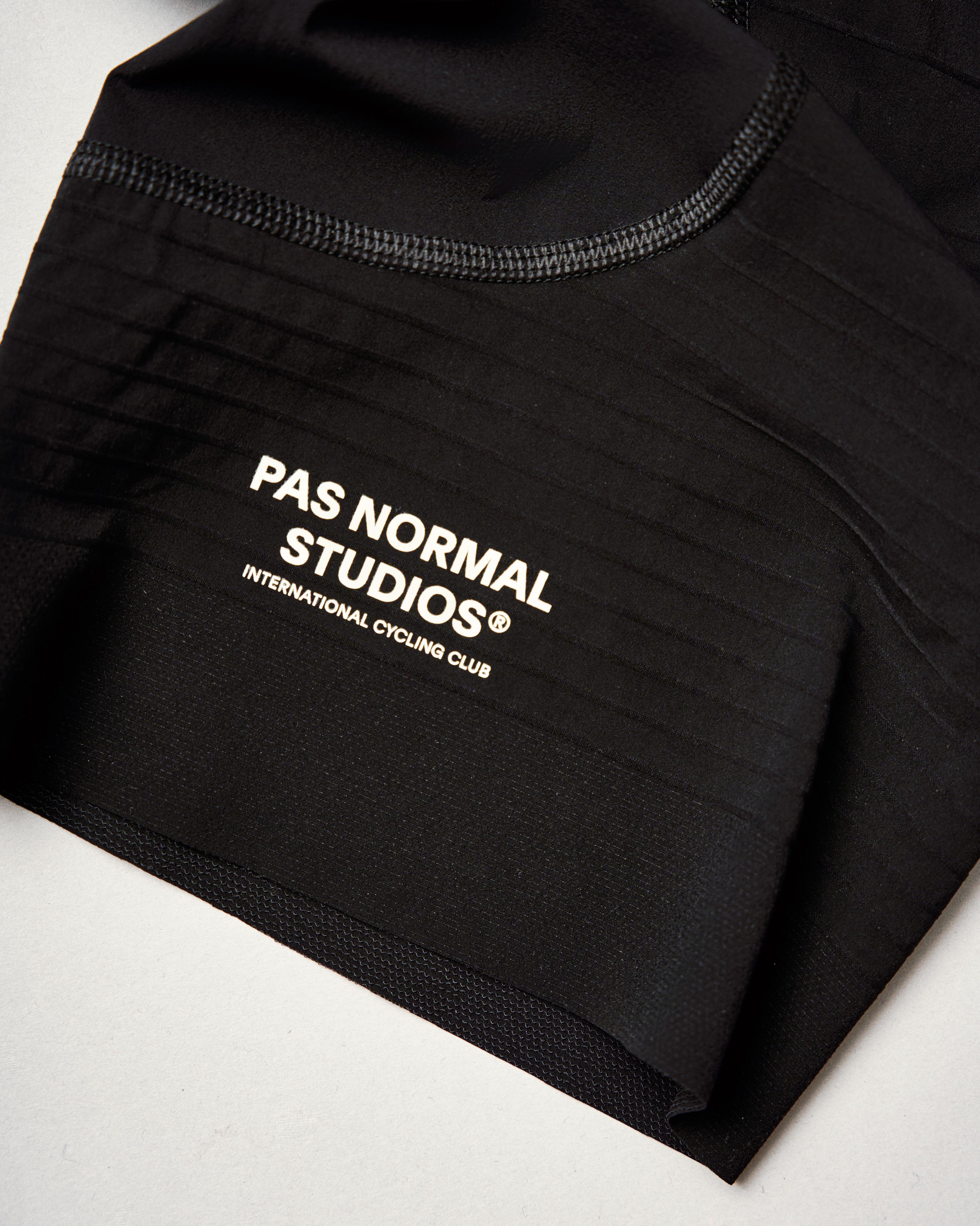 Black PAS Mechanism Pro bibs, detail view showing white chest logo and mesh straps