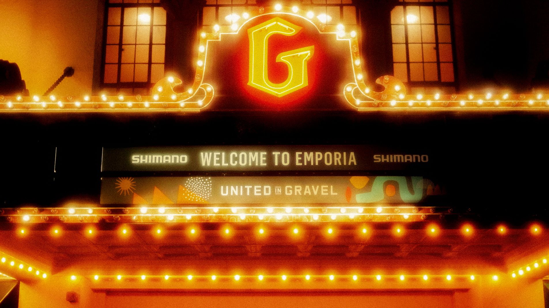Illuminated theater marquee welcoming visitors to Emporia with cycling event branding and decorative lights
