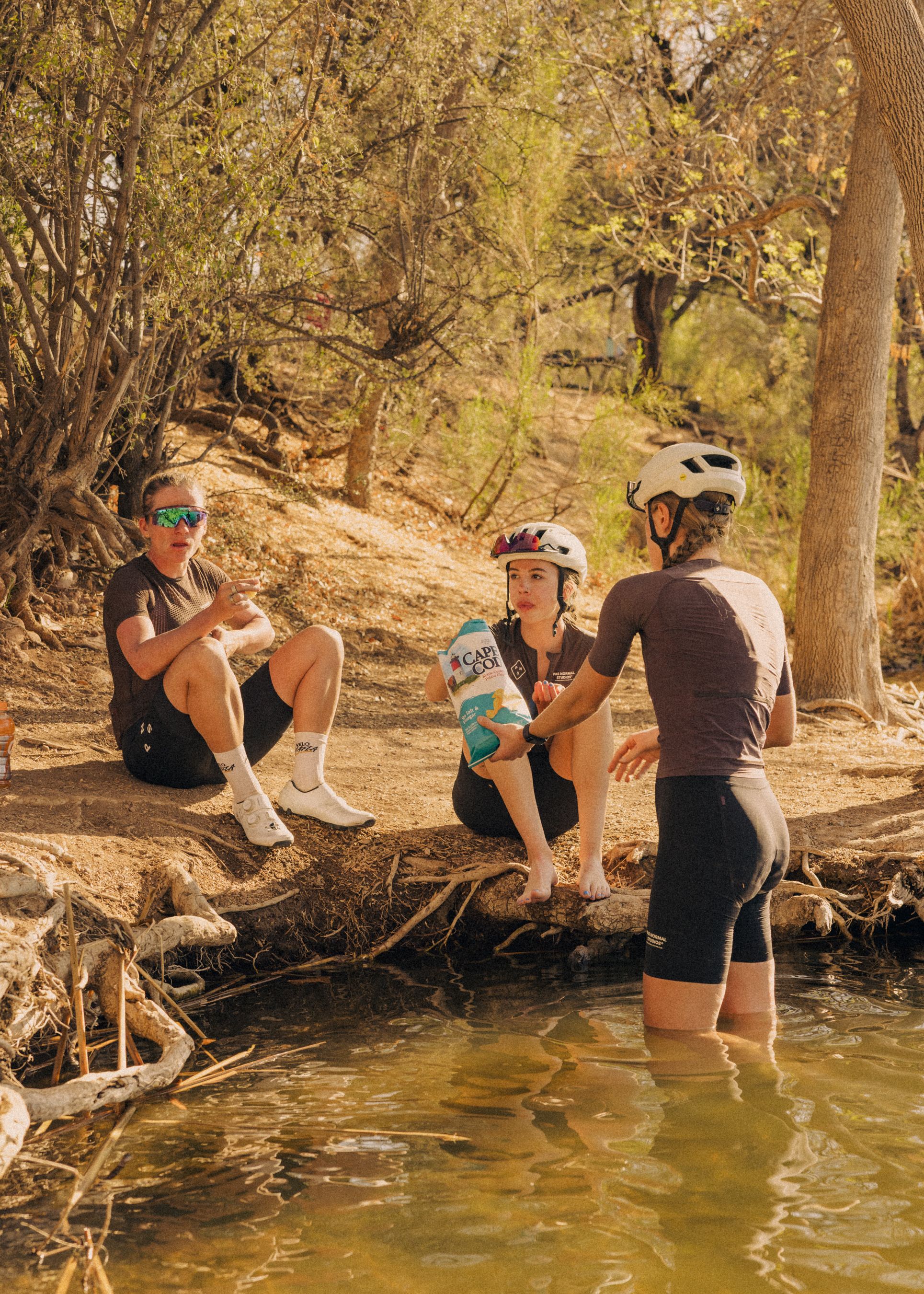 Three cyclists taking a break by a stream during desert training ride in Tucson