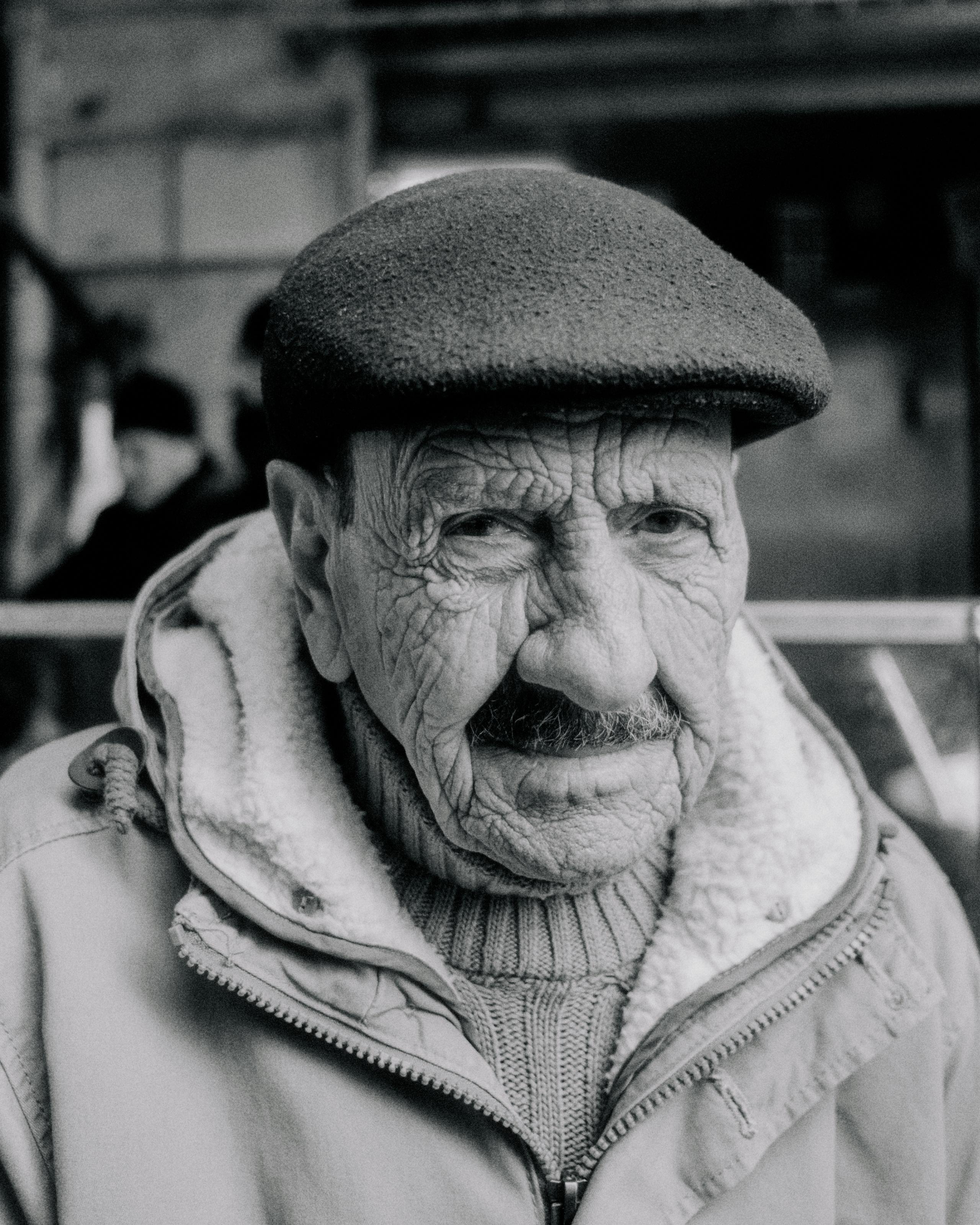 Black and white portrait of elderly man in flat cap and jacket