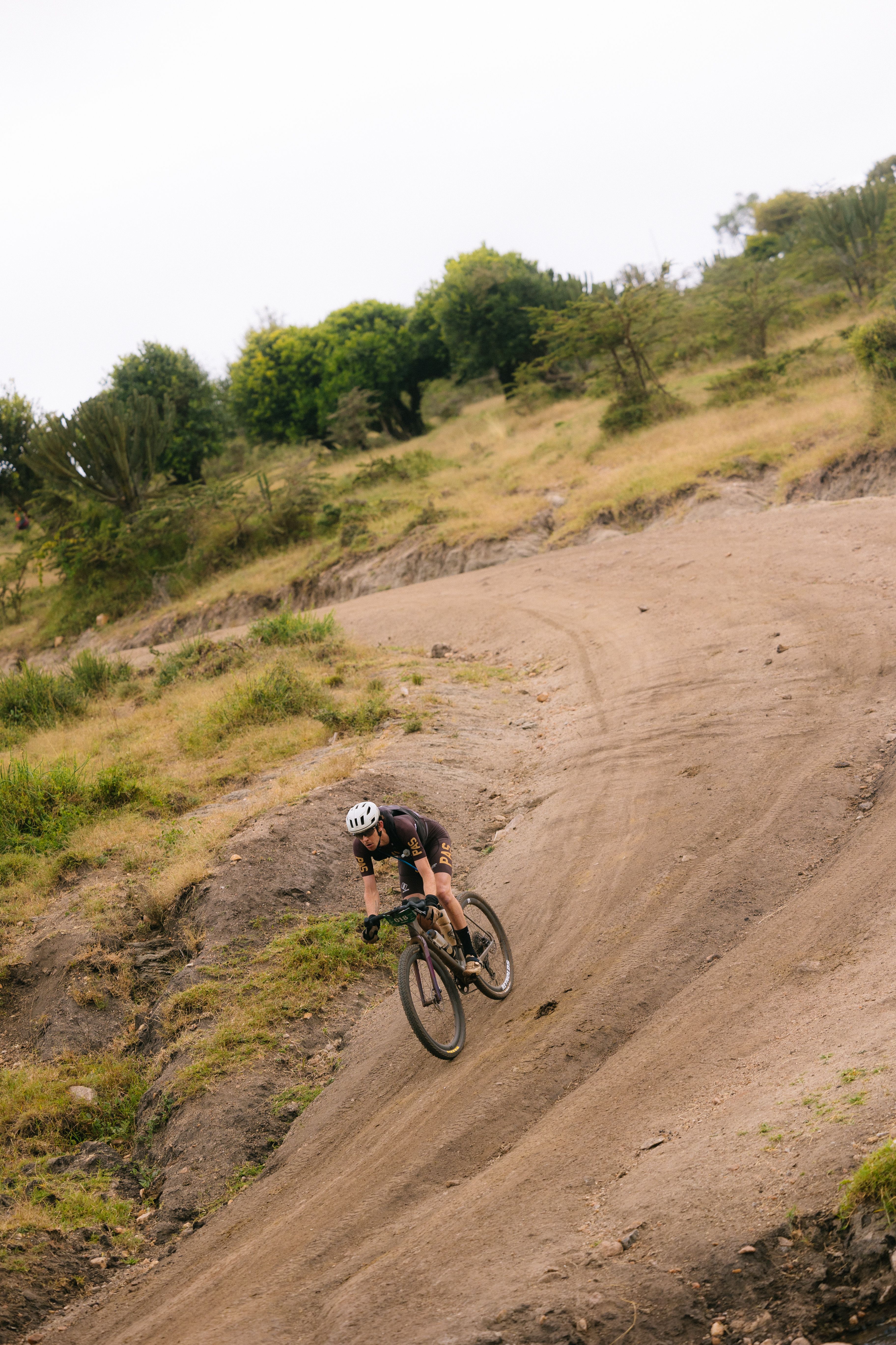 Model wearing dark gravel cycling kit navigating dirt trail turn on mountain bike