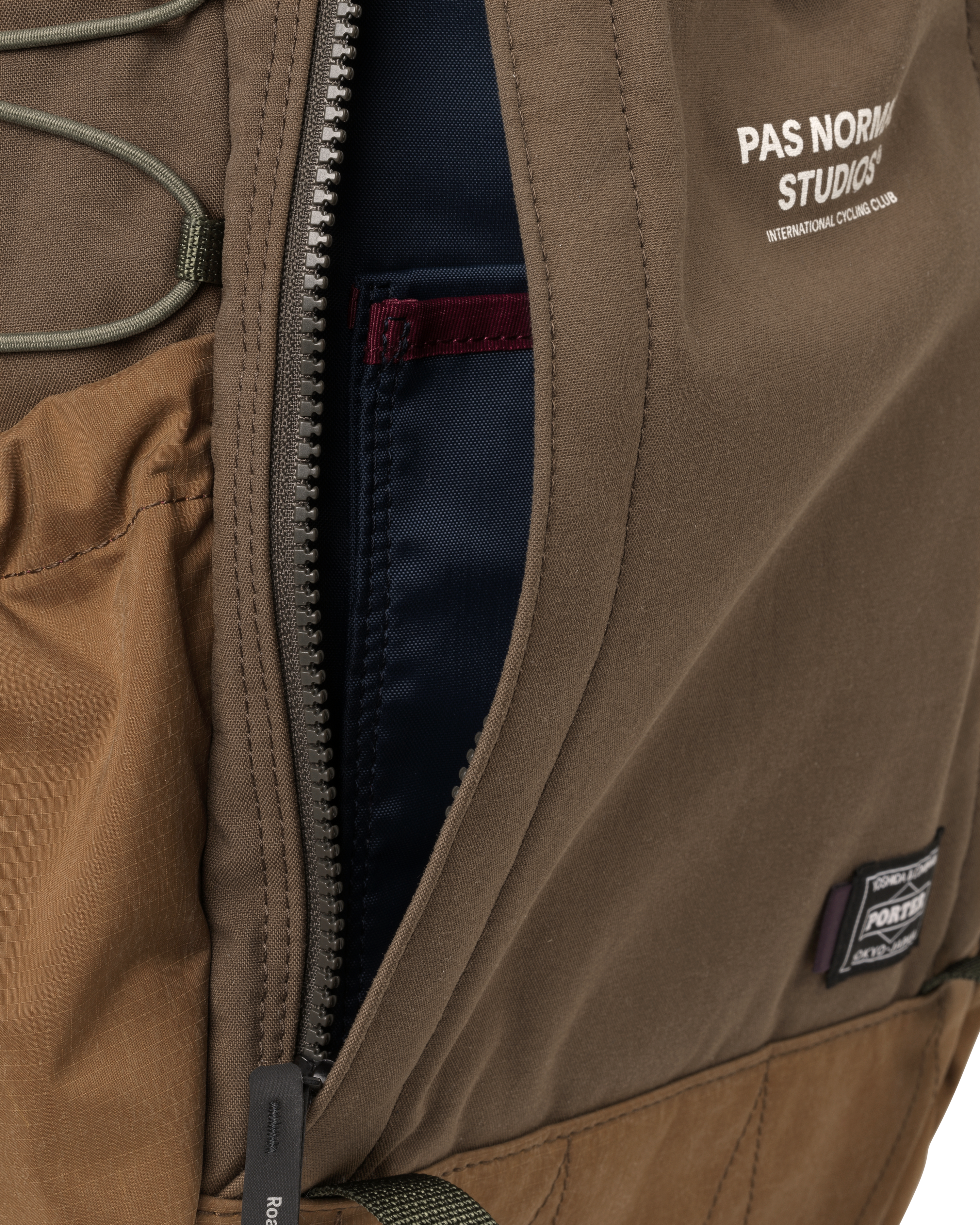Light Brown Porter-Yoshida backpack, detail view of open main zip compartment with navy interior lining and Porter badge