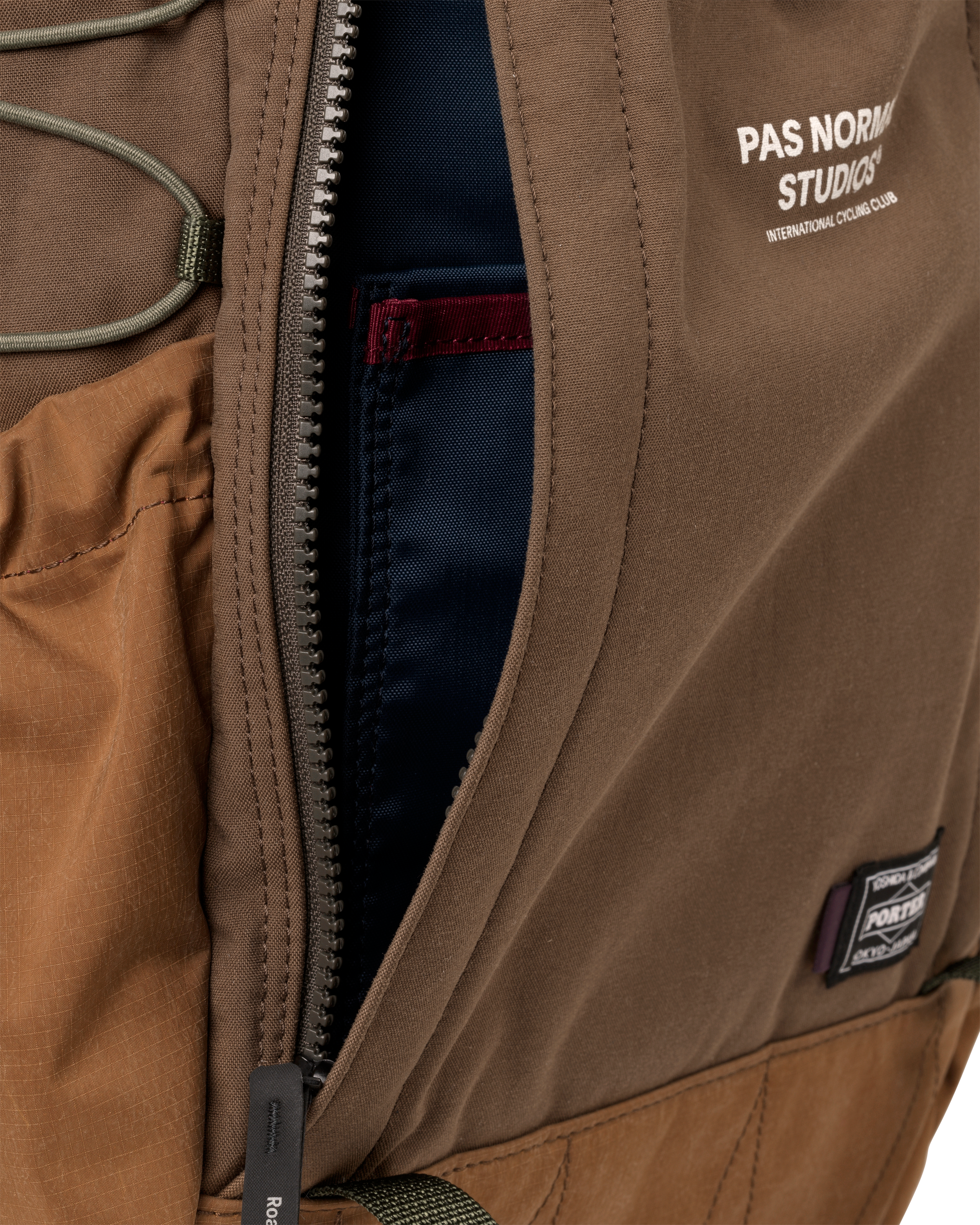 Light Brown Porter-Yoshida backpack, detail view of open main zip compartment with navy interior lining and Porter badge