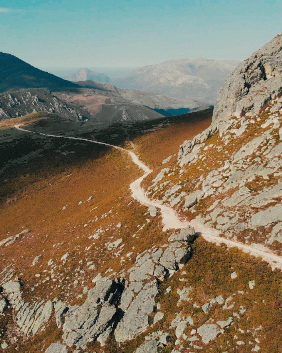 Mountain cycling route winding through rocky terrain with distant peaks and turquoise sky