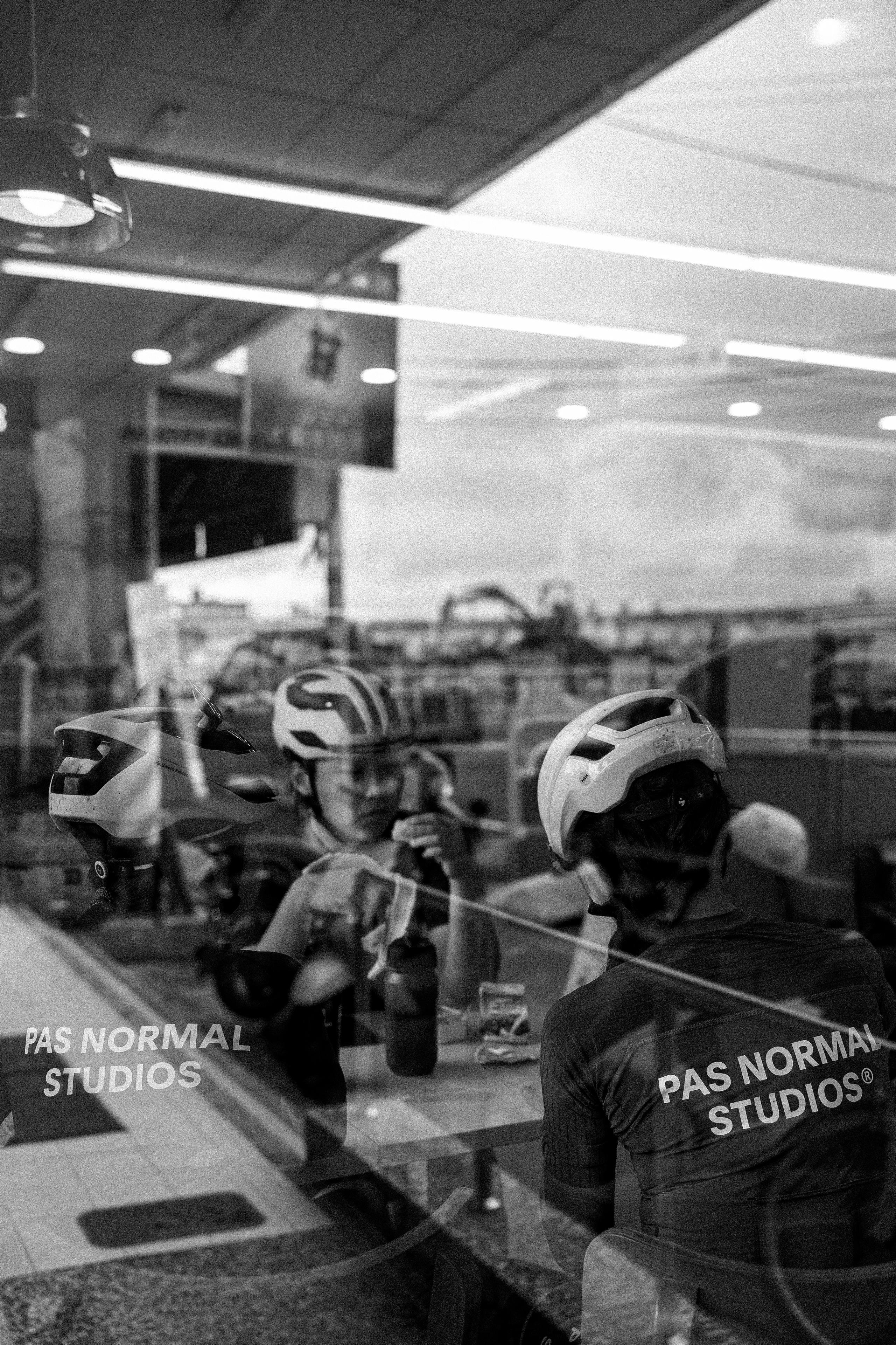 Cyclists in aerodynamic helmets reflected in window, black and white photograph