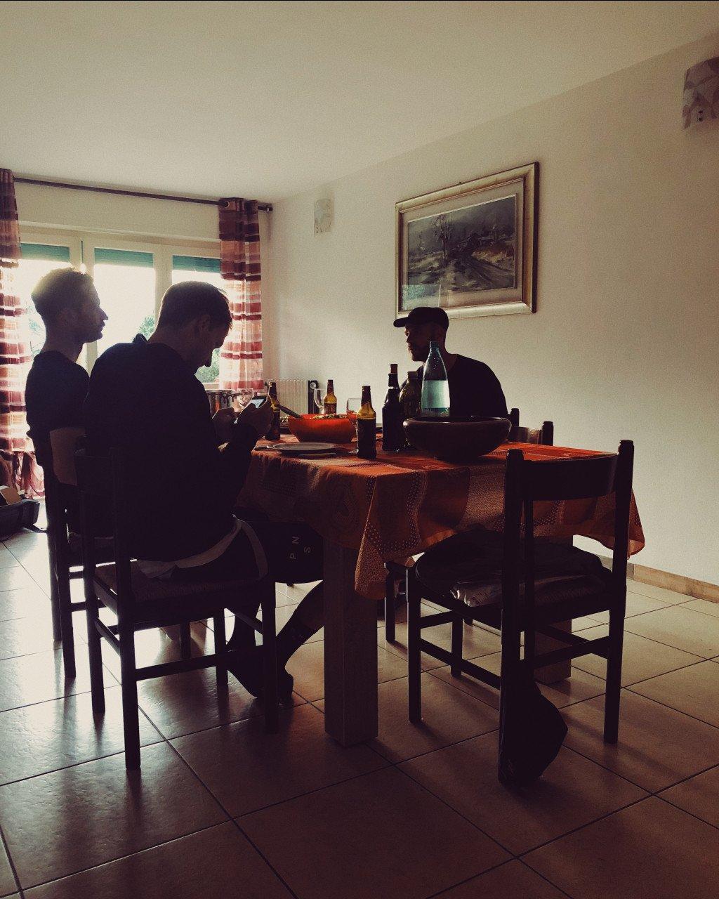 Three cyclists sharing a meal at dining table in rustic interior setting