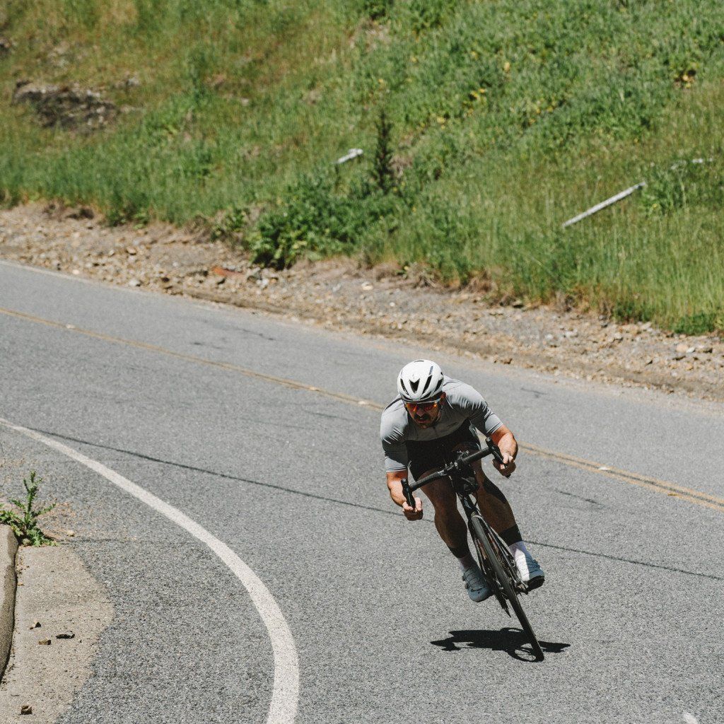 Model wearing grey aerodynamic cycling kit on time trial bike on rural road