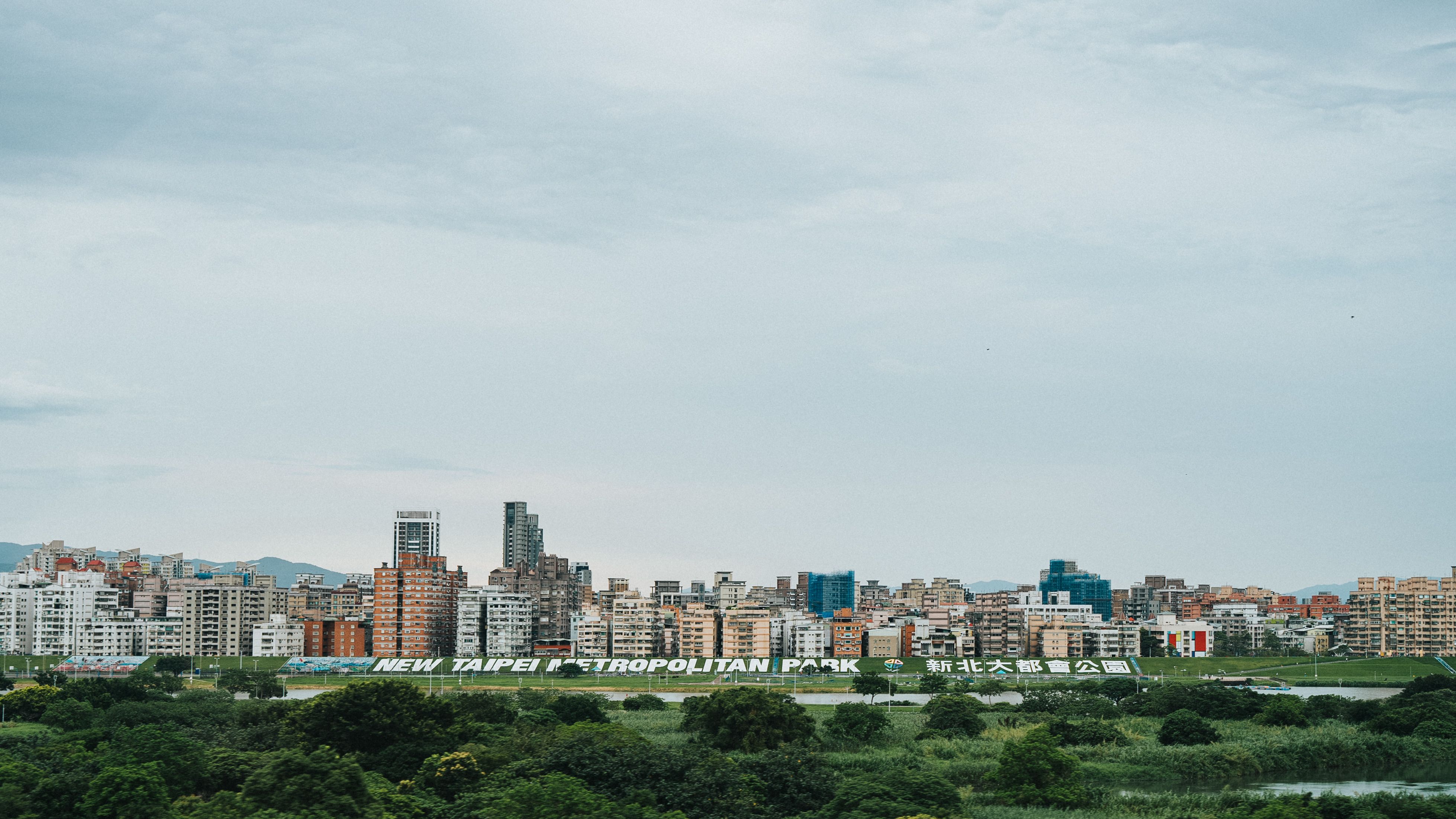Urban cityscape with apartment buildings and green foreground under cloudy sky
