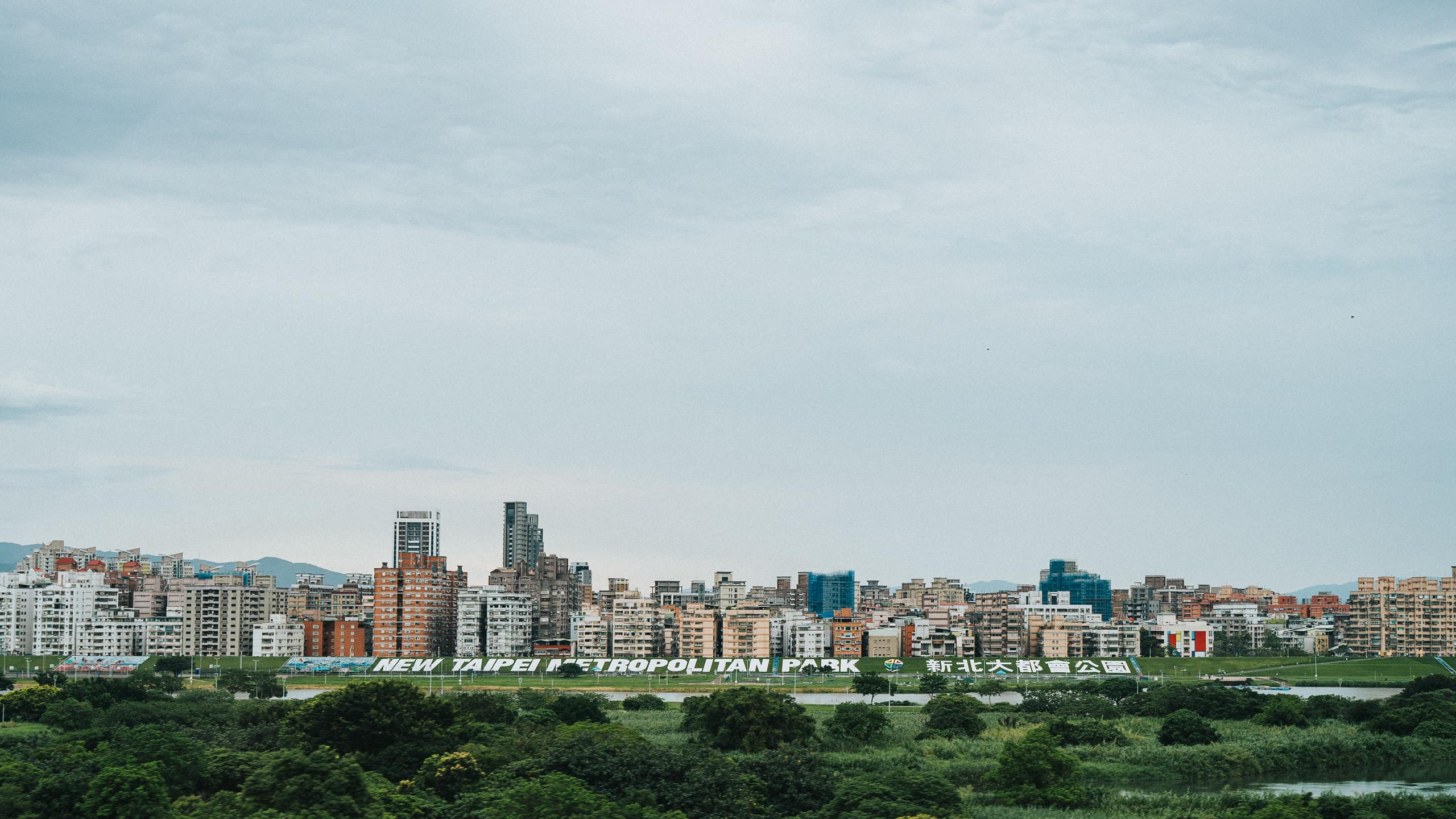 Urban cityscape with apartment buildings and green foreground under cloudy sky