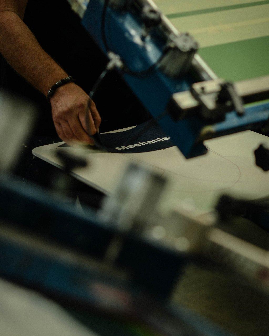 Hand cutting dark fabric with collection branding in manufacturing workshop