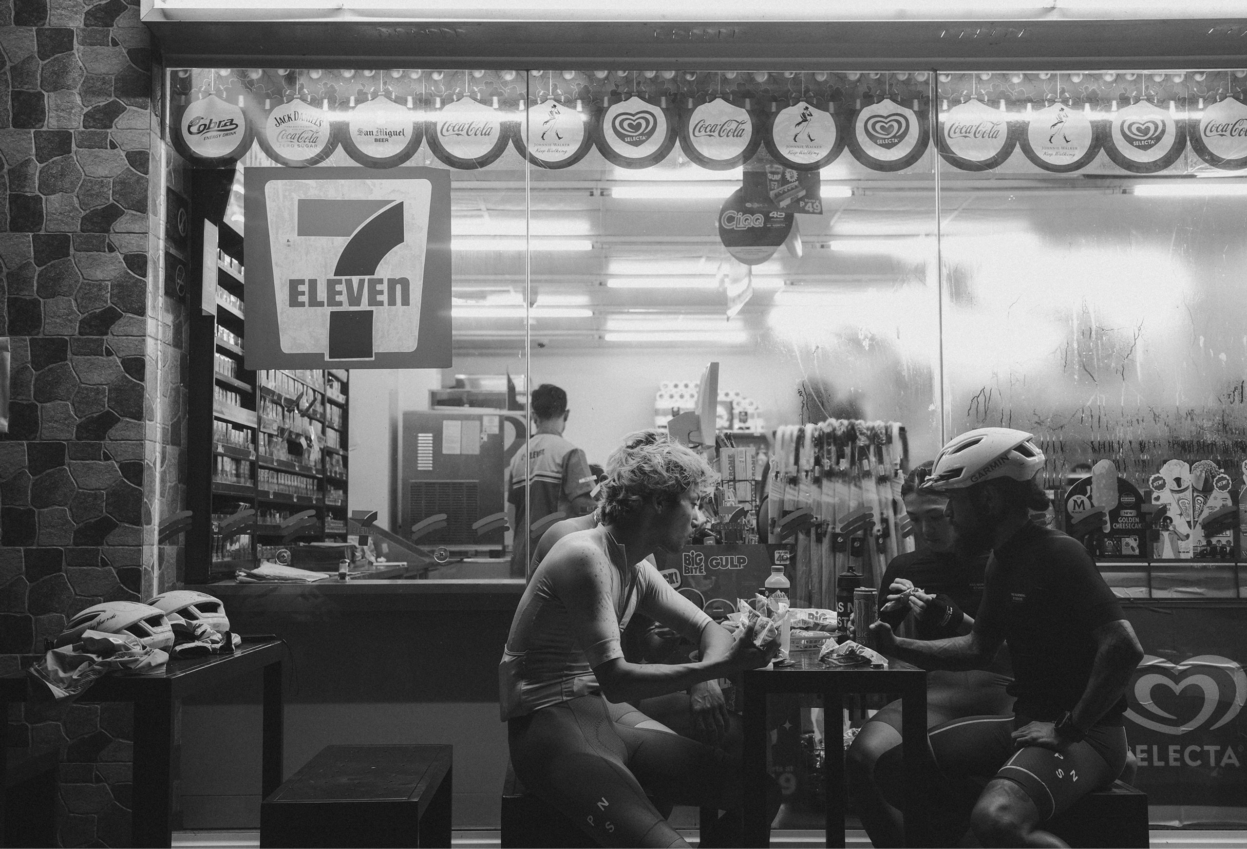 Cyclists taking a break at convenience store during ride, black and white photography