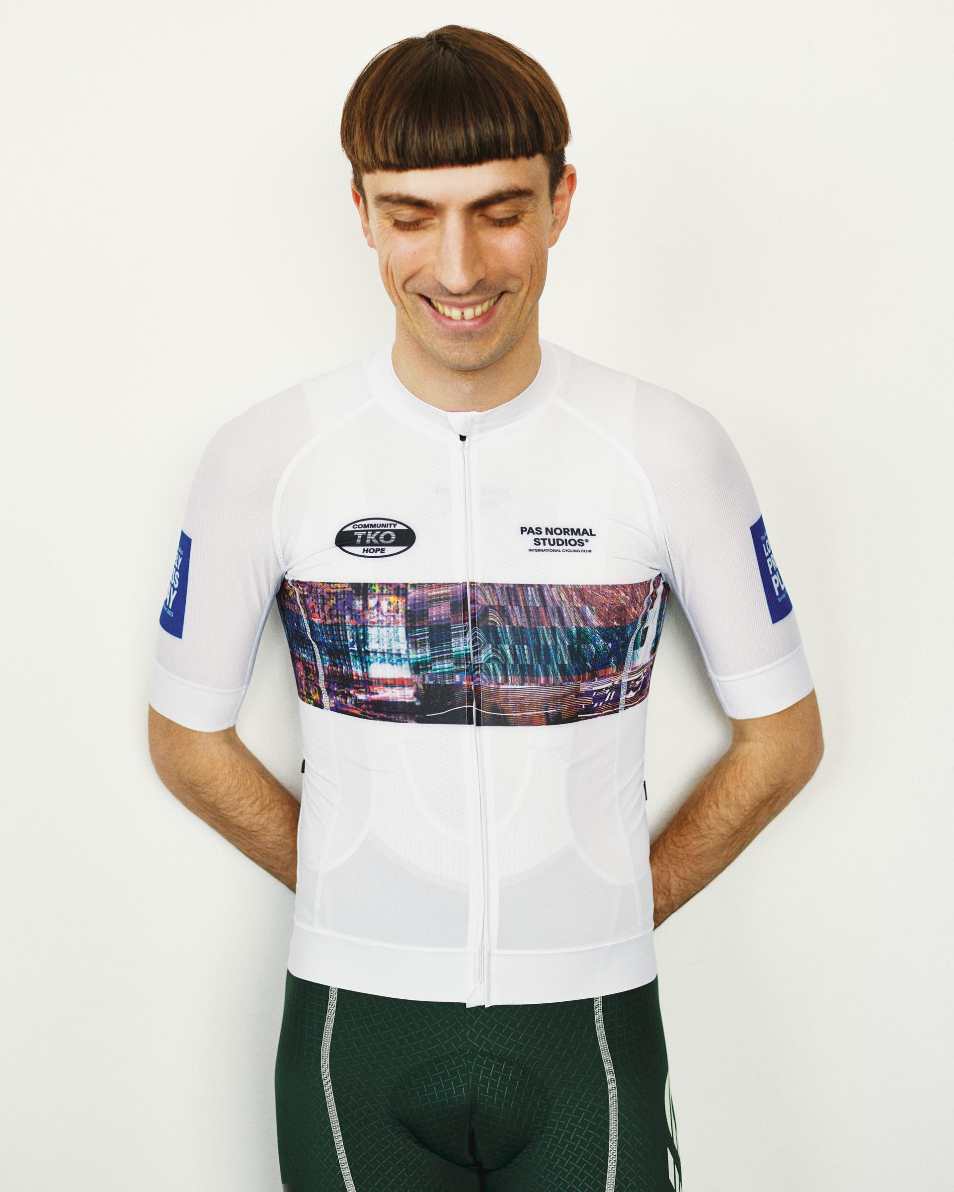 White T.K.O. Mechanism cycling jersey on model, front view with cityscape graphic band and blue sleeve patch
