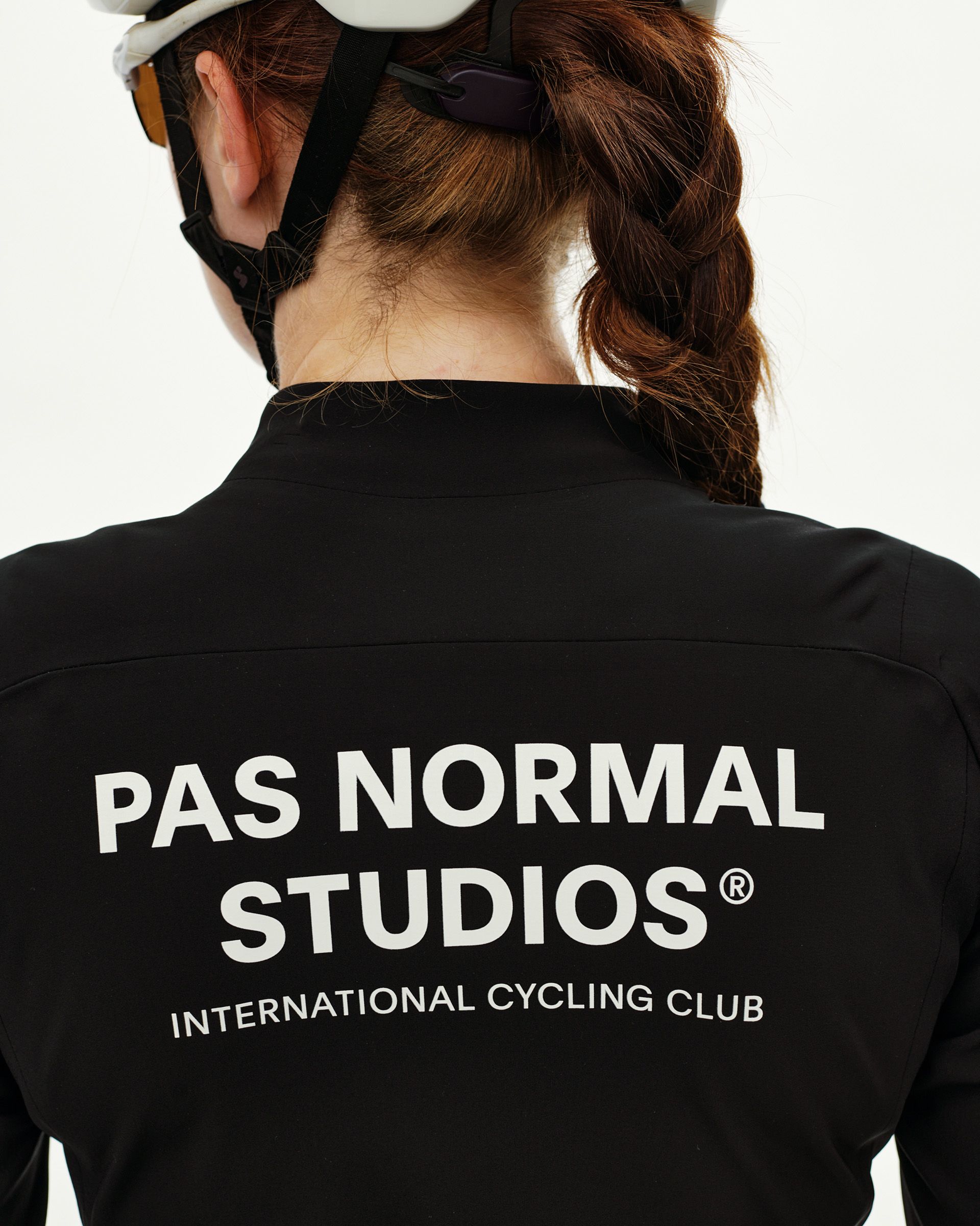 Black Mechanism Thermal cycling jacket on model, rear view with white logo print across back
