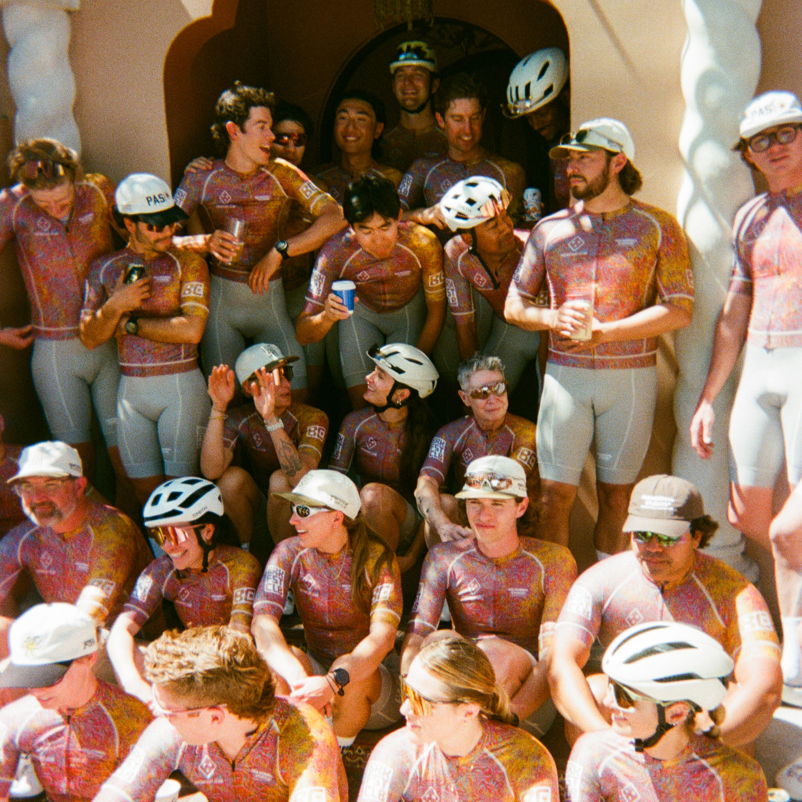 Cycling team wearing matching orange paisley jerseys and grey shorts gathered for group photo