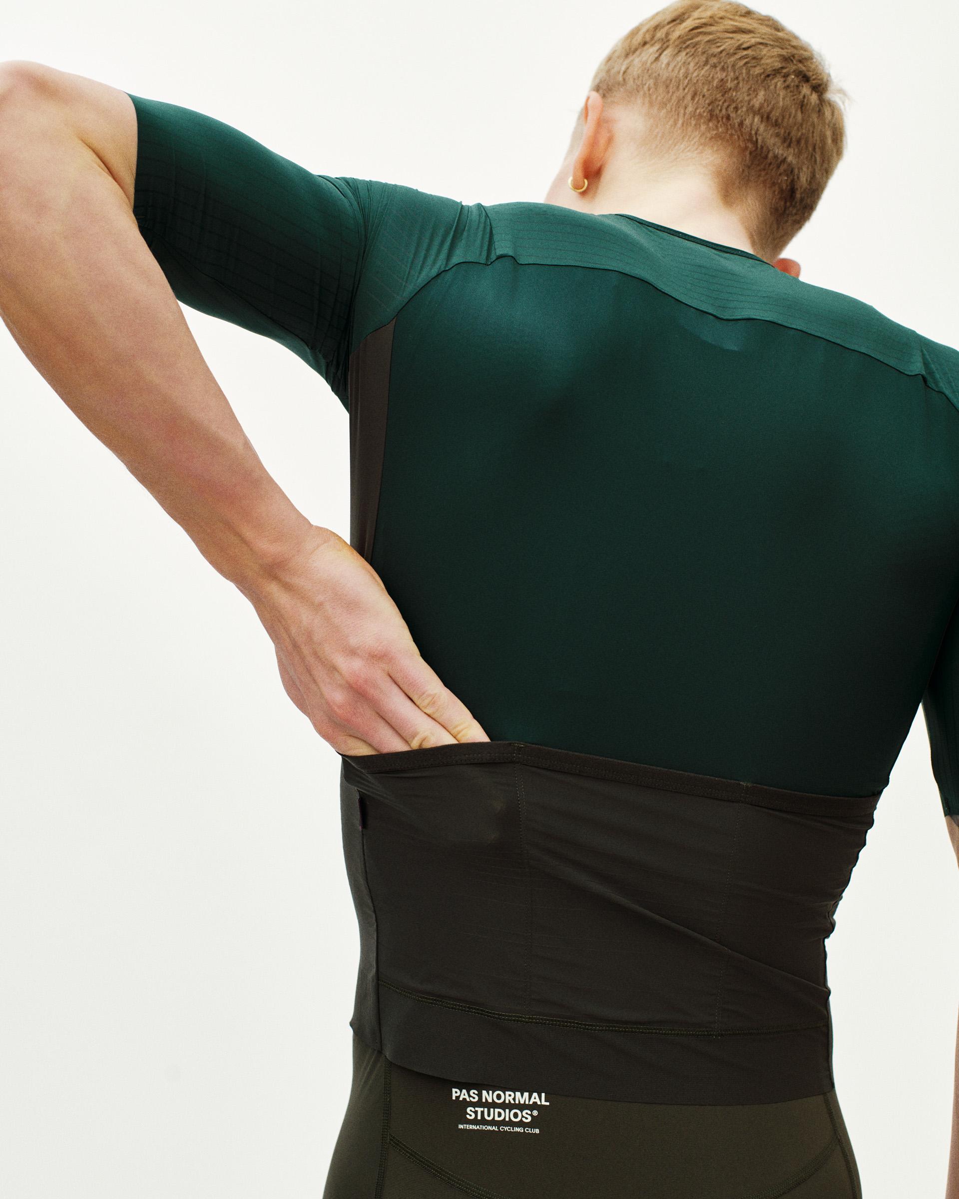 Green Mechanism Pro cycling jersey on model, rear three-quarter view with contrast side panels