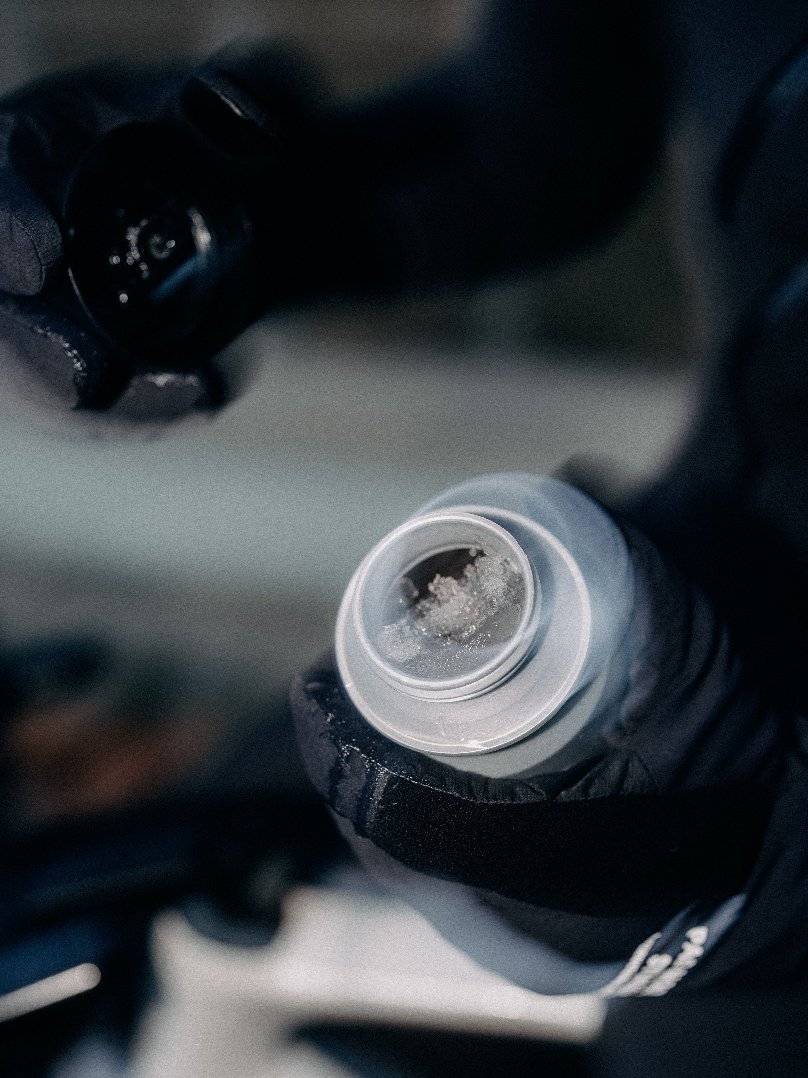 Black cycling bottle with white cap being held during ride