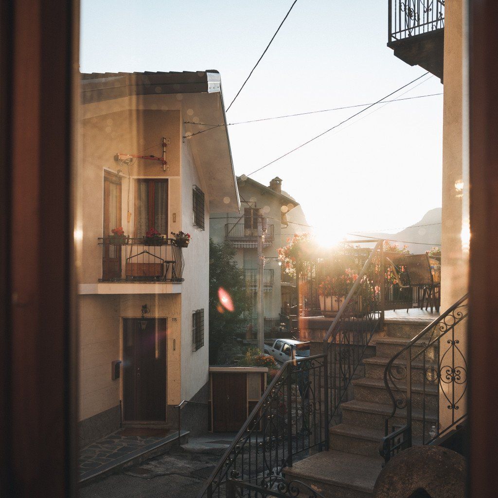 European village street scene with traditional buildings and warm sunlight through archway