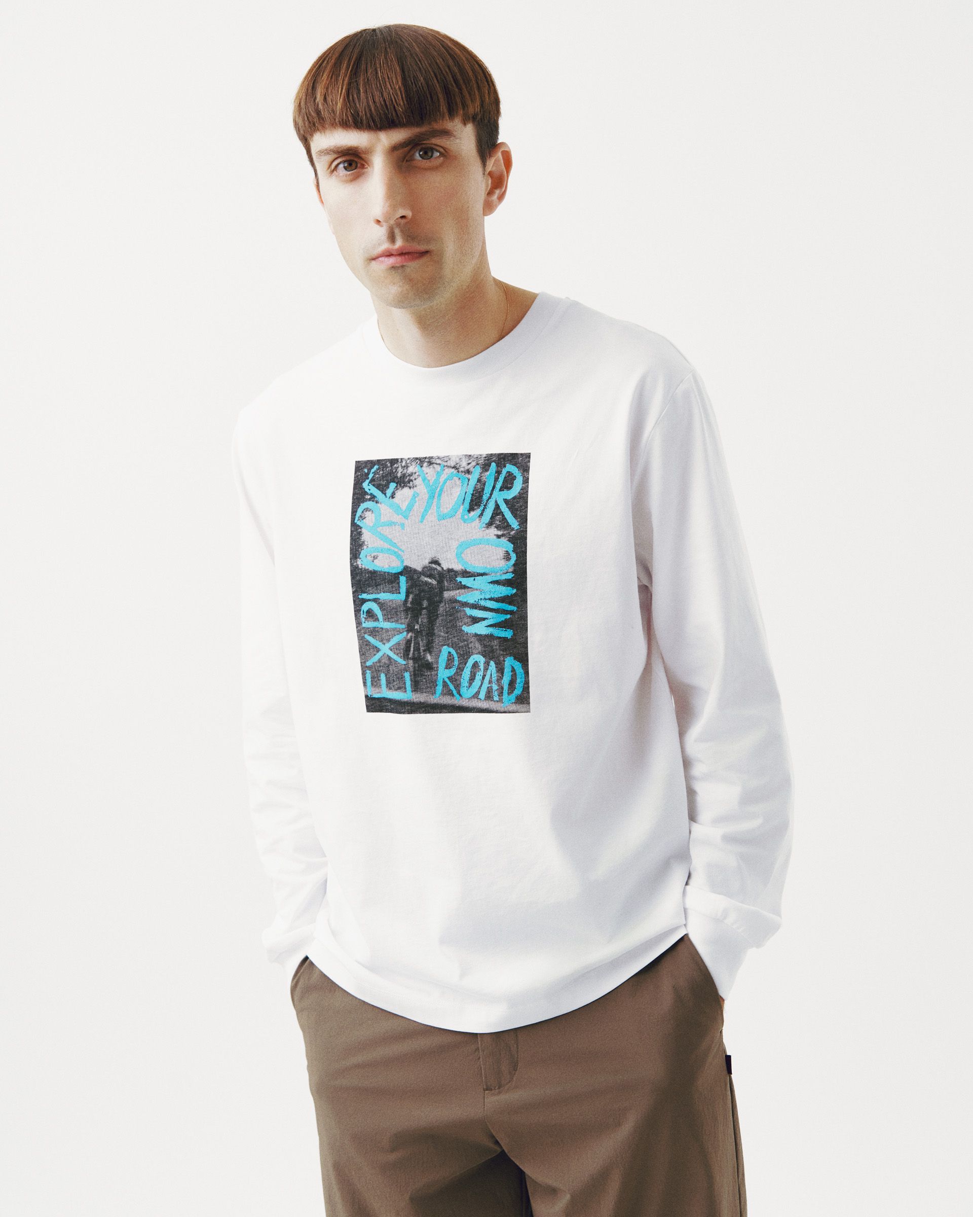 White Off-Race Graphic long sleeve t-shirt on model with blue chest print reading "EXPLORE YOUR OWN ROAD"