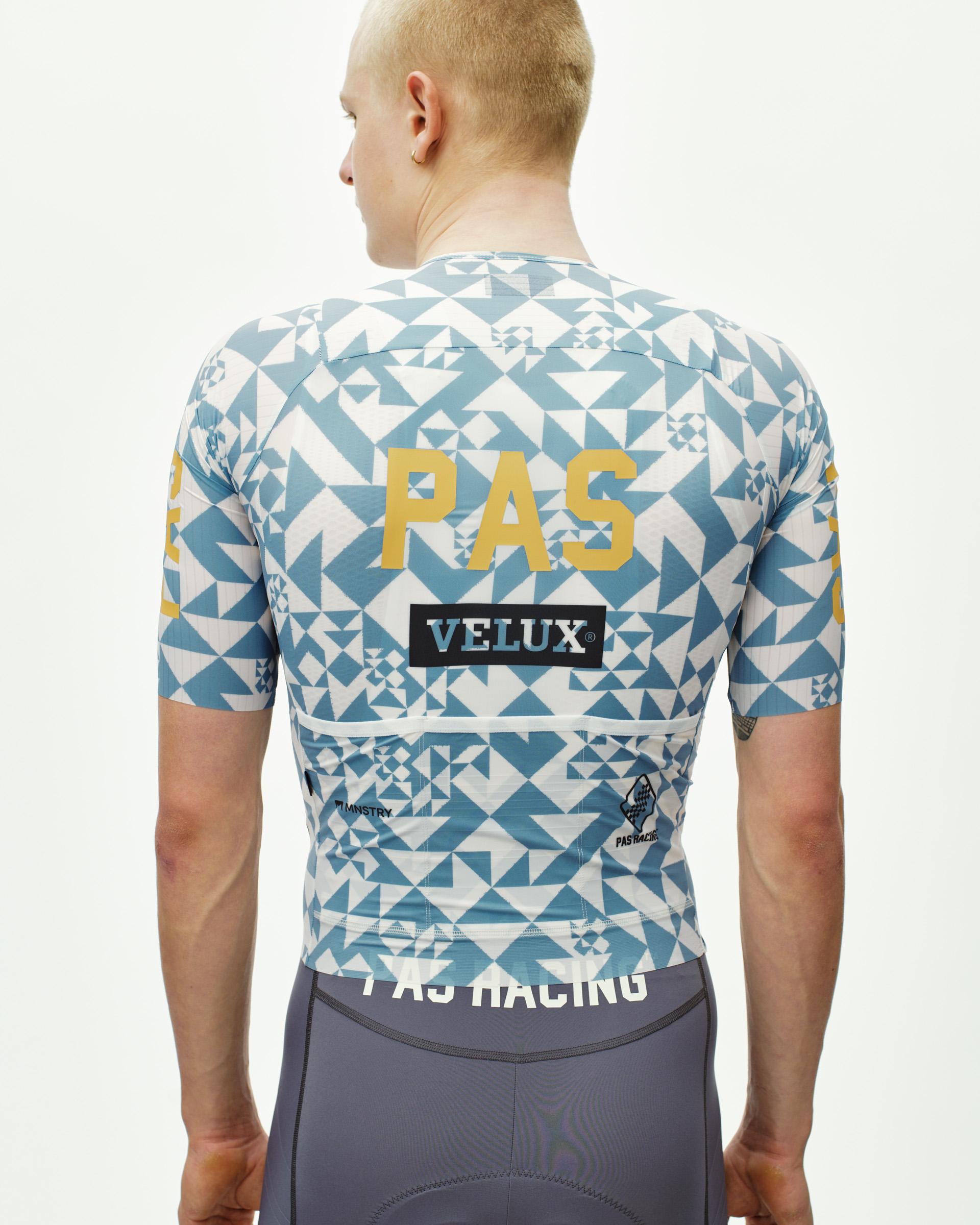 Origami Light Blue PAS Mechanism Pro cycling jersey on model, rear view with geometric print and gold PAS back text