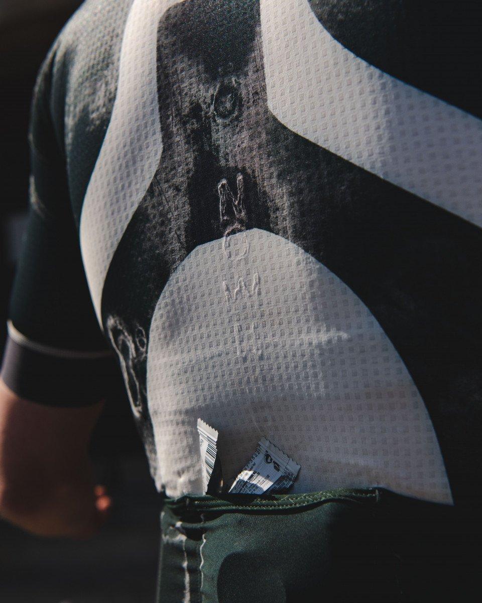 Cycling jersey detail showing white mesh fabric with textured pattern and brand lettering
