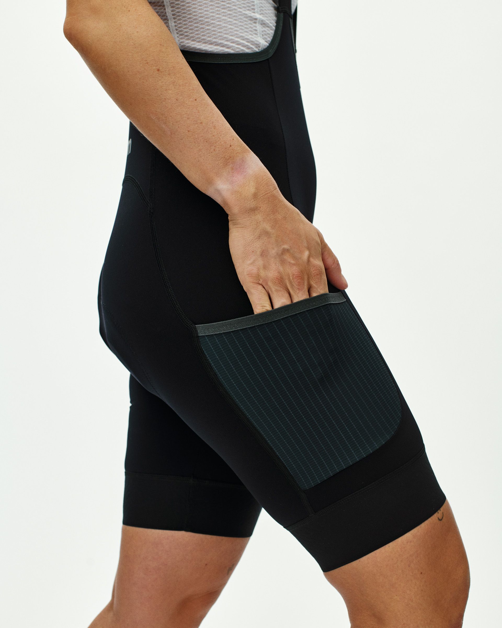 Black Escapism cycling bibs on model showing side cargo pocket with grid pattern flap