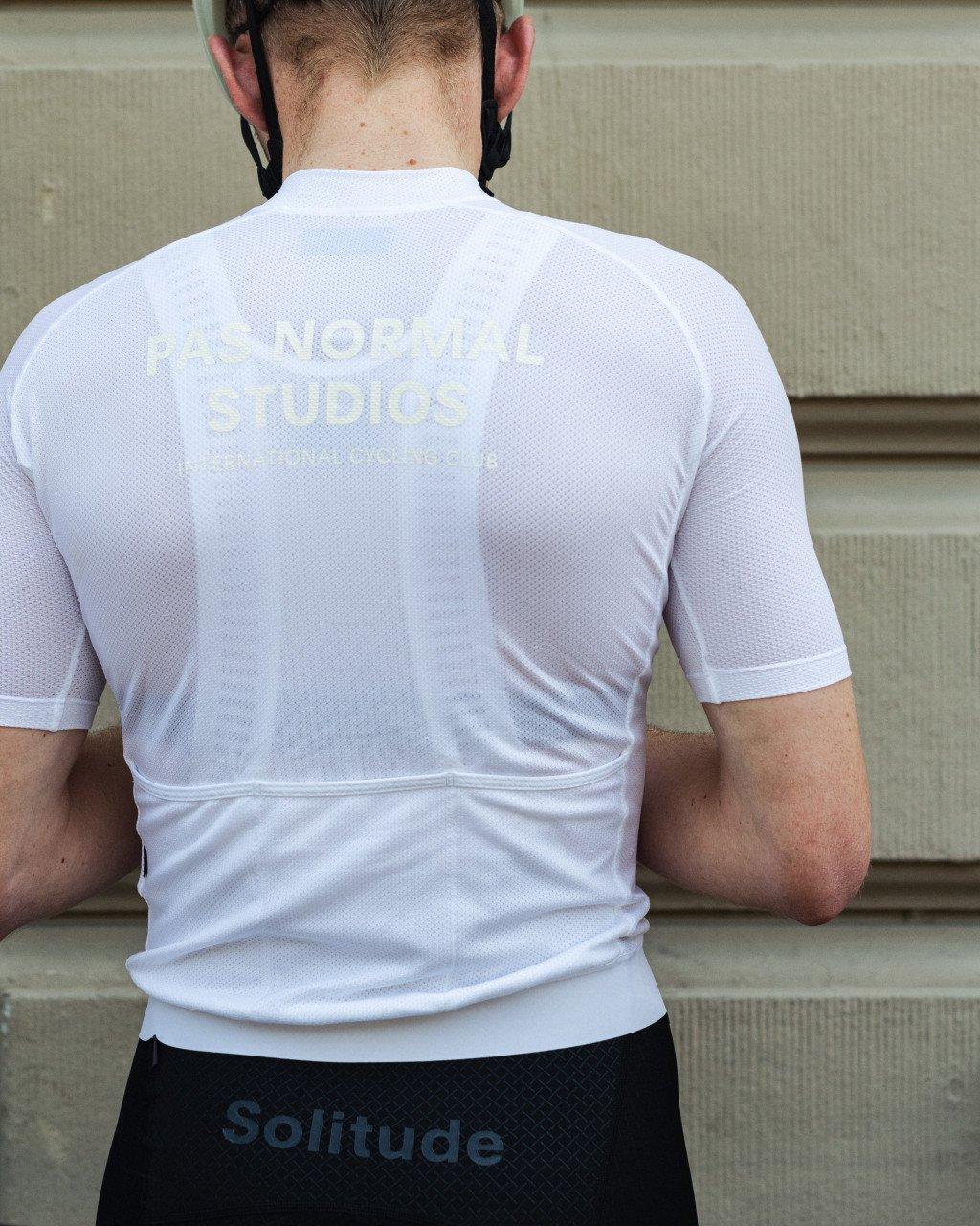 Model wearing white Solitude cycling jersey with back branding, paired with black shorts