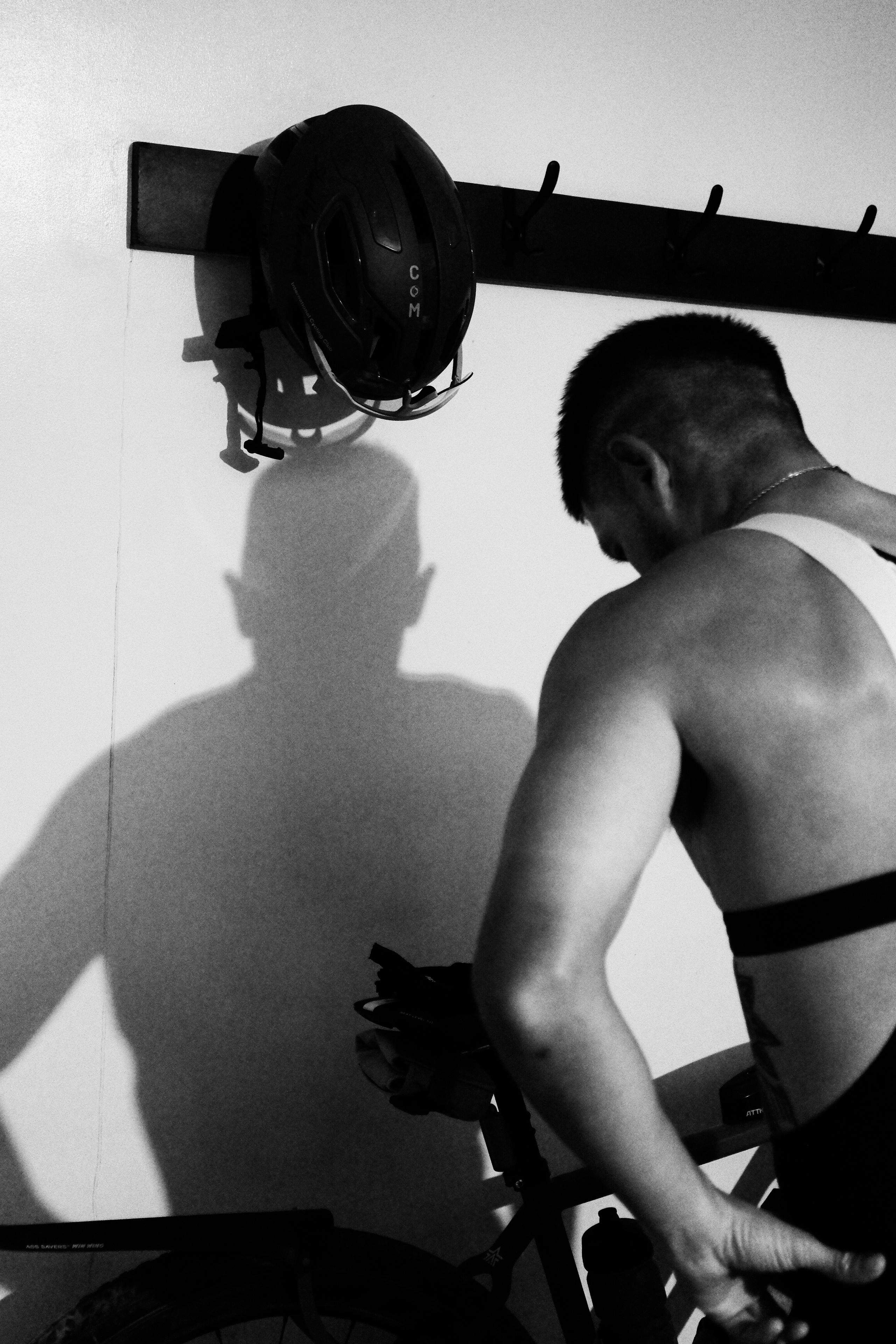 Model training indoors on stationary bike wearing black cycling shorts, black and white photography