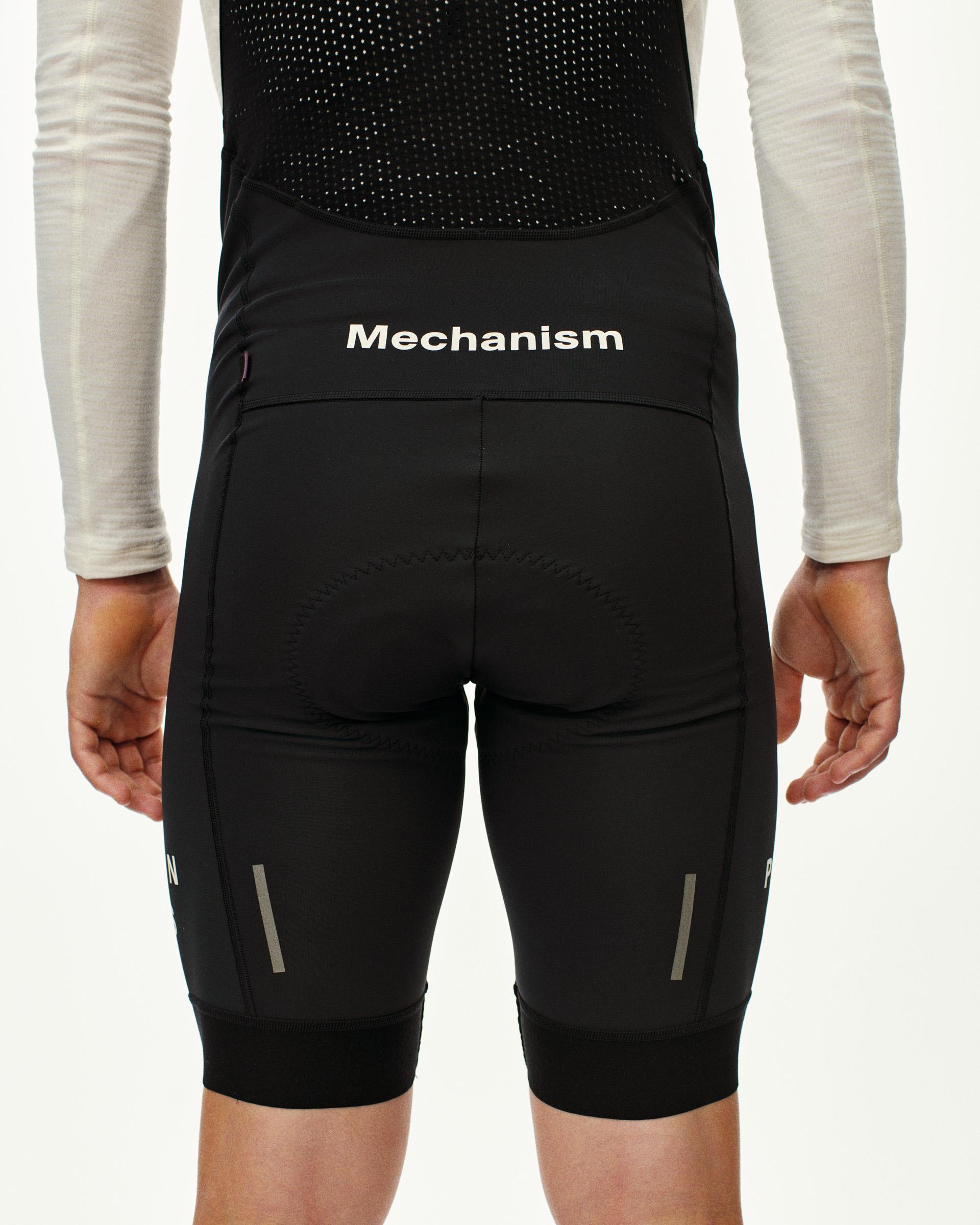 Black Mechanism Deep Winter cycling bibs, rear view on model with reflective leg strips
